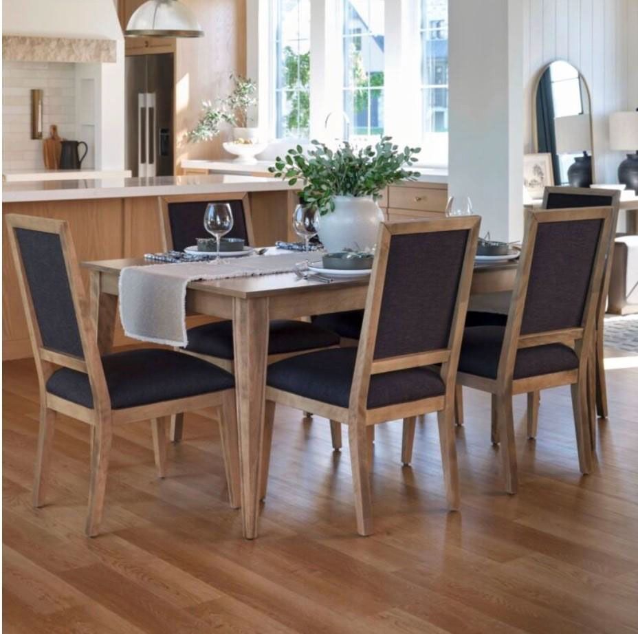 Modern dining room with a wooden table, four upholstered chairs, and a vase centerpiece by a bright window