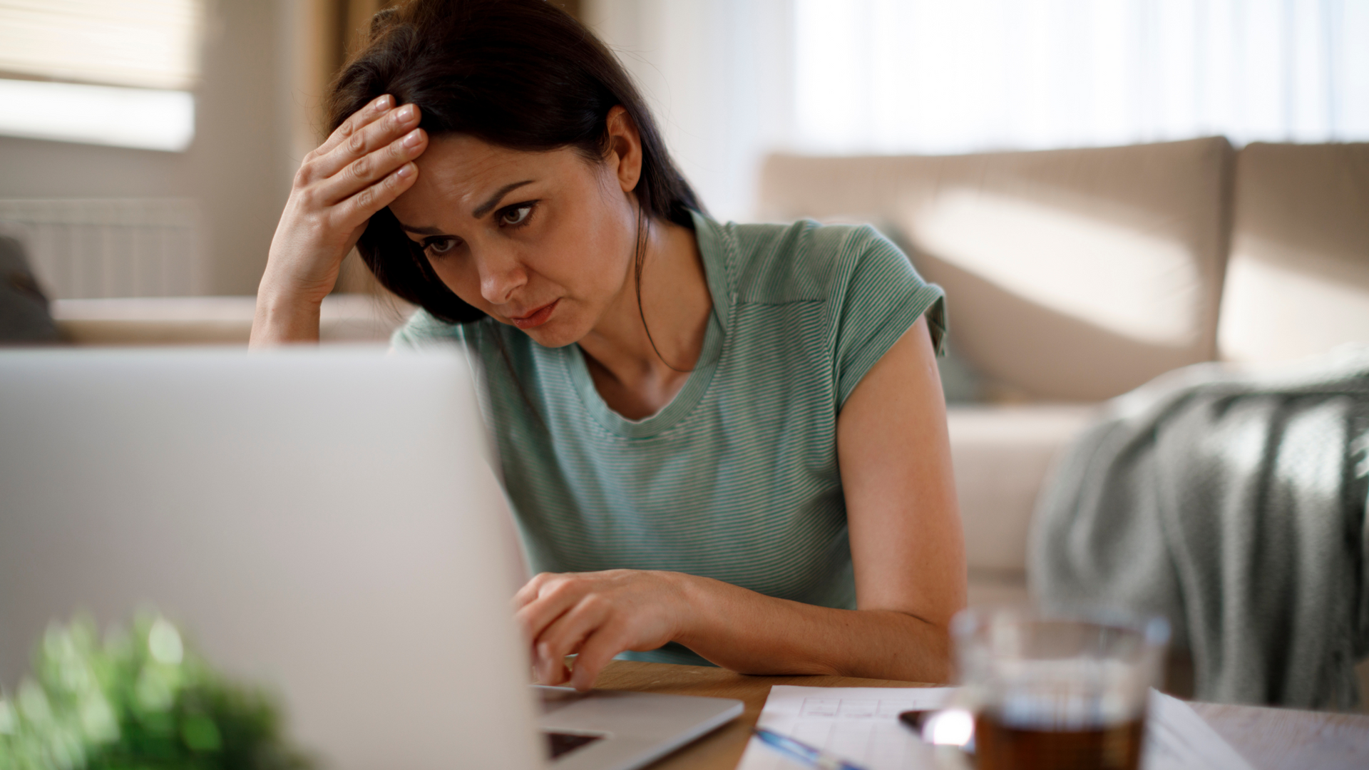 A woman is sitting at a table using a laptop computer.
