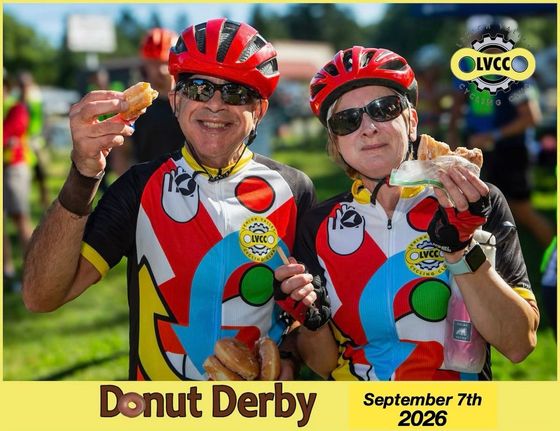 Two cyclists in helmets eating donuts at the 