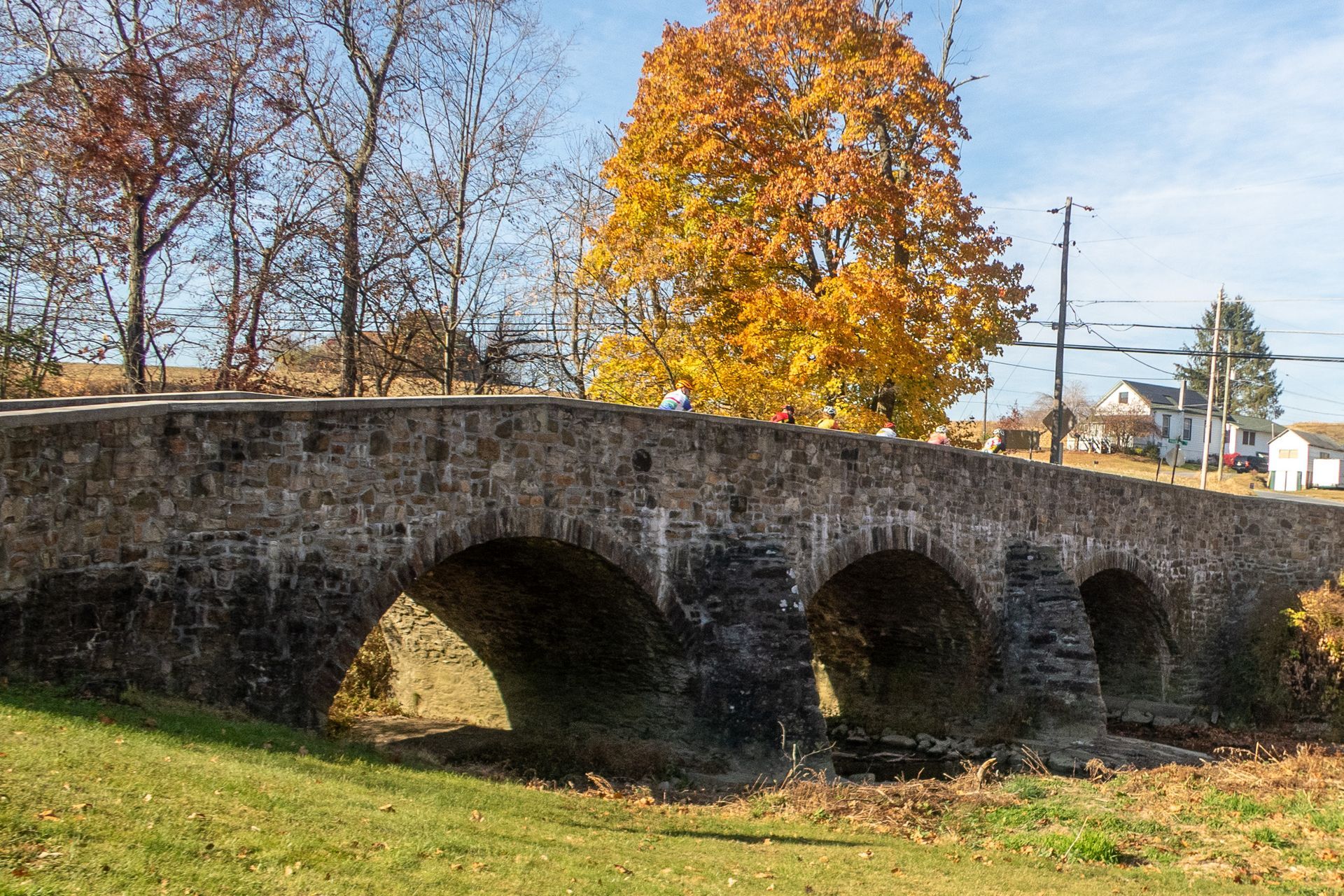 Stone arch bridge with autumn trees in the background.