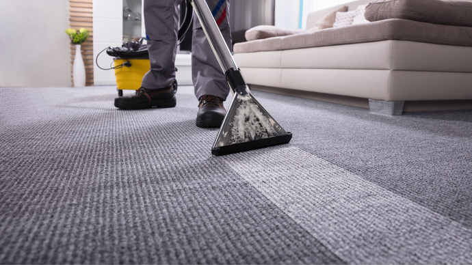A man is using a vacuum cleaner to clean a carpet in a living room.