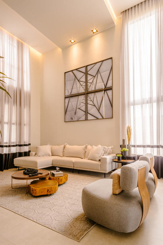A living room with a couch , chair , coffee table and paintings on the wall.
