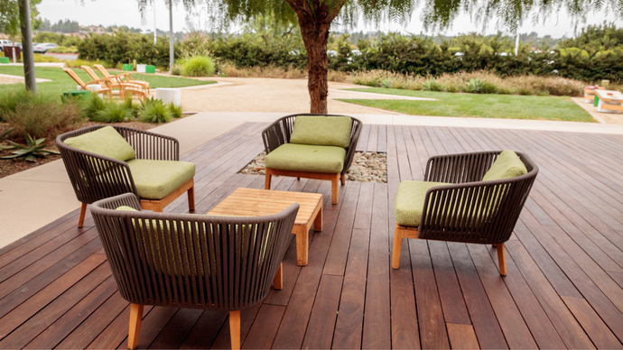 A wooden deck with chairs and a table under a tree