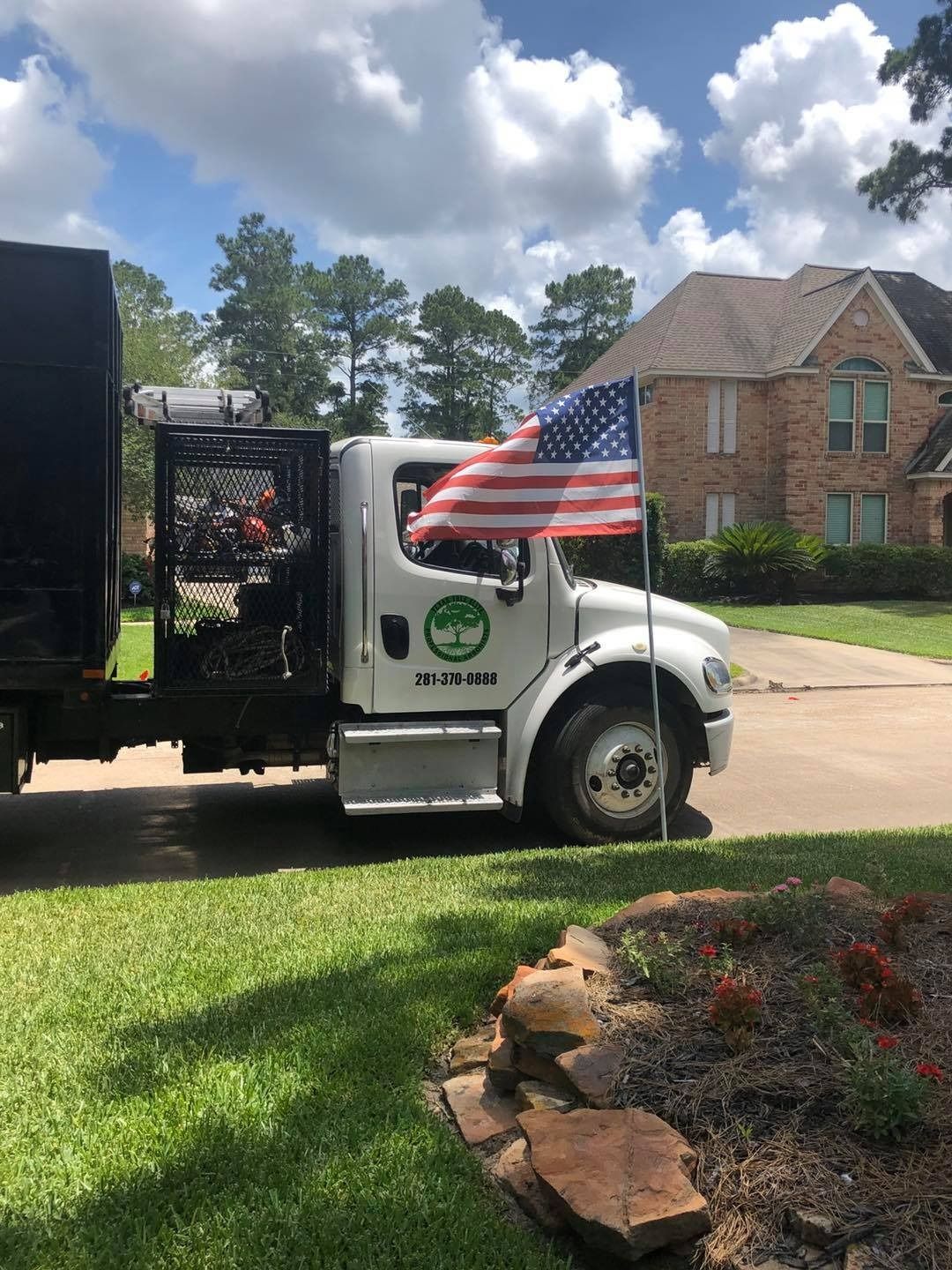 White delivery truck with an American flag parked on a suburban street under a sunny sky