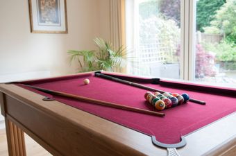 A pool table with balls and cues in a living room