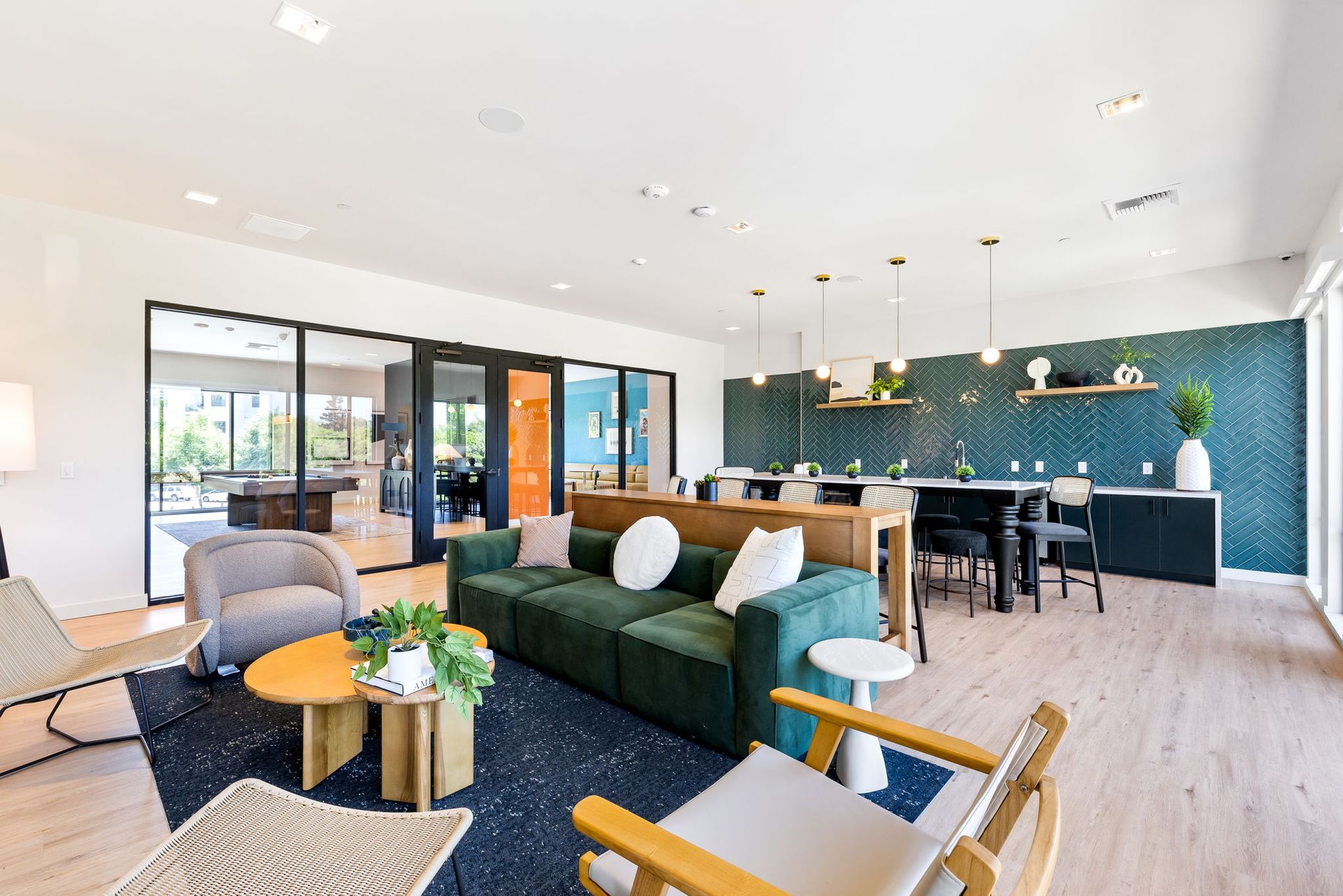 A clubhouse with a green couch , chairs , tables and a table.