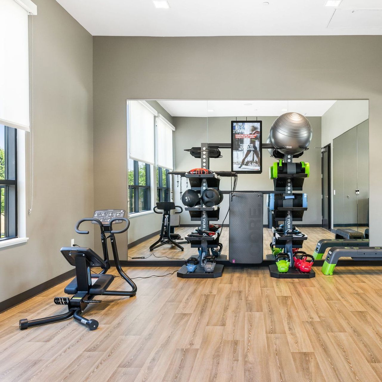 A gym with a lot of equipment and a large mirror at The Hayley, offers apartments in Sacramento, CA.