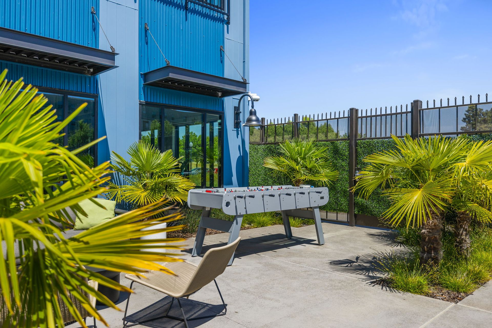 A patio with a table and chairs in front of a blue building.