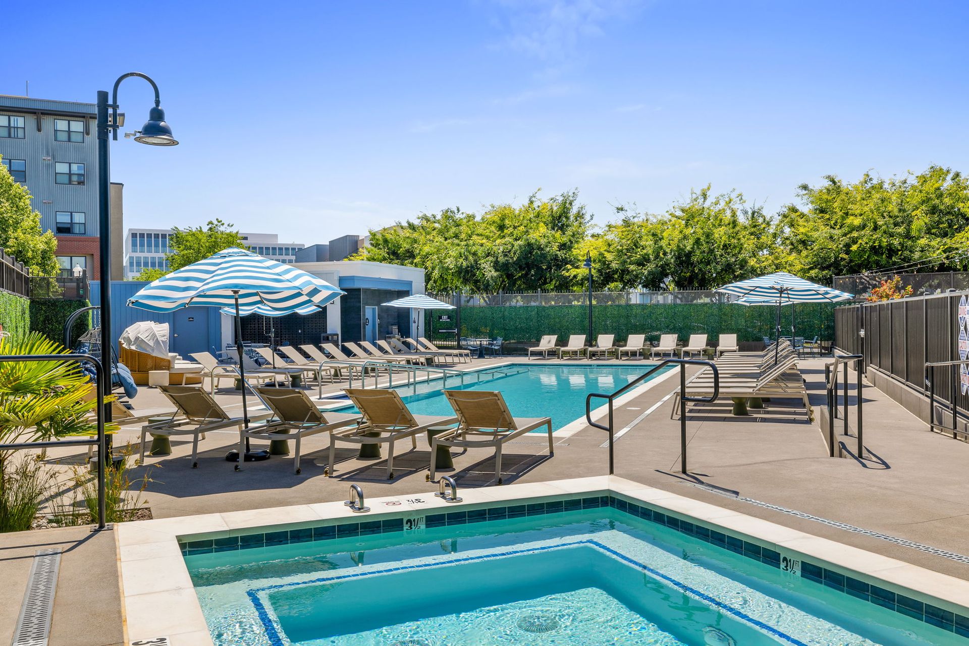 A large swimming pool surrounded by chairs and umbrellas at The Hayley, offers apartments in Sacramento, CA.