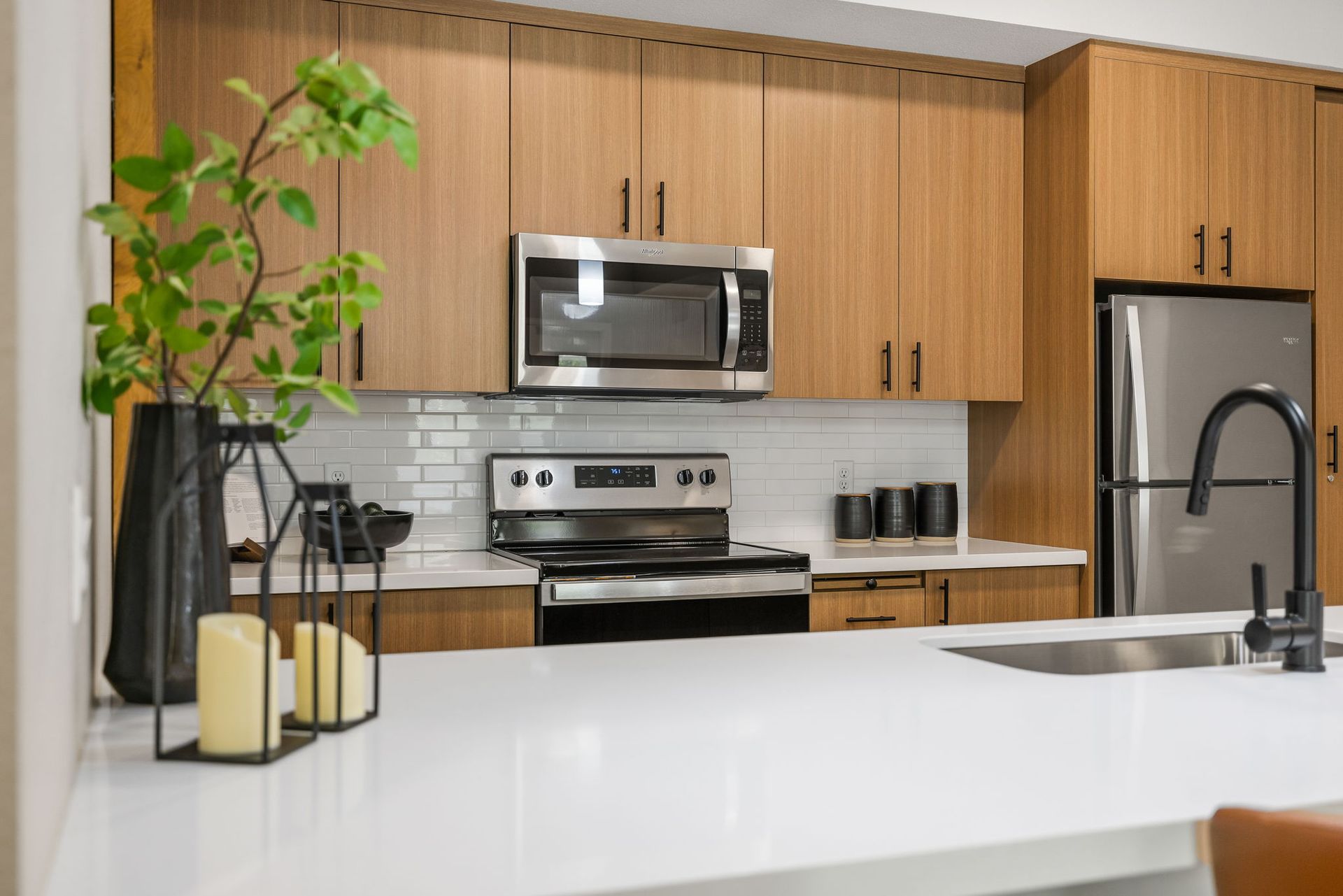 A kitchen with wooden cabinets , stainless steel appliances , a sink , and a microwave.