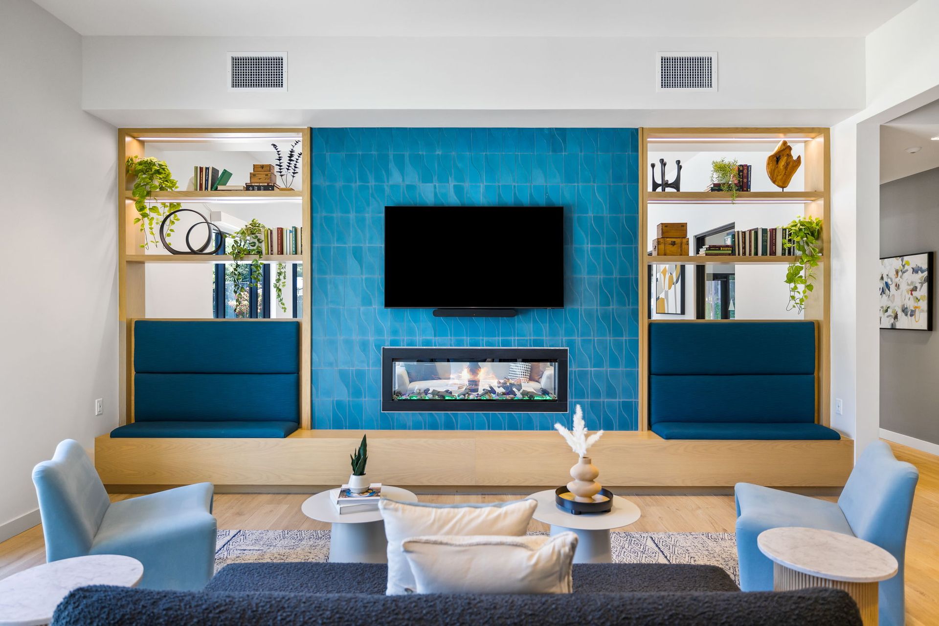 A clubhouse with a couch , chairs , tables and a flat screen tv.