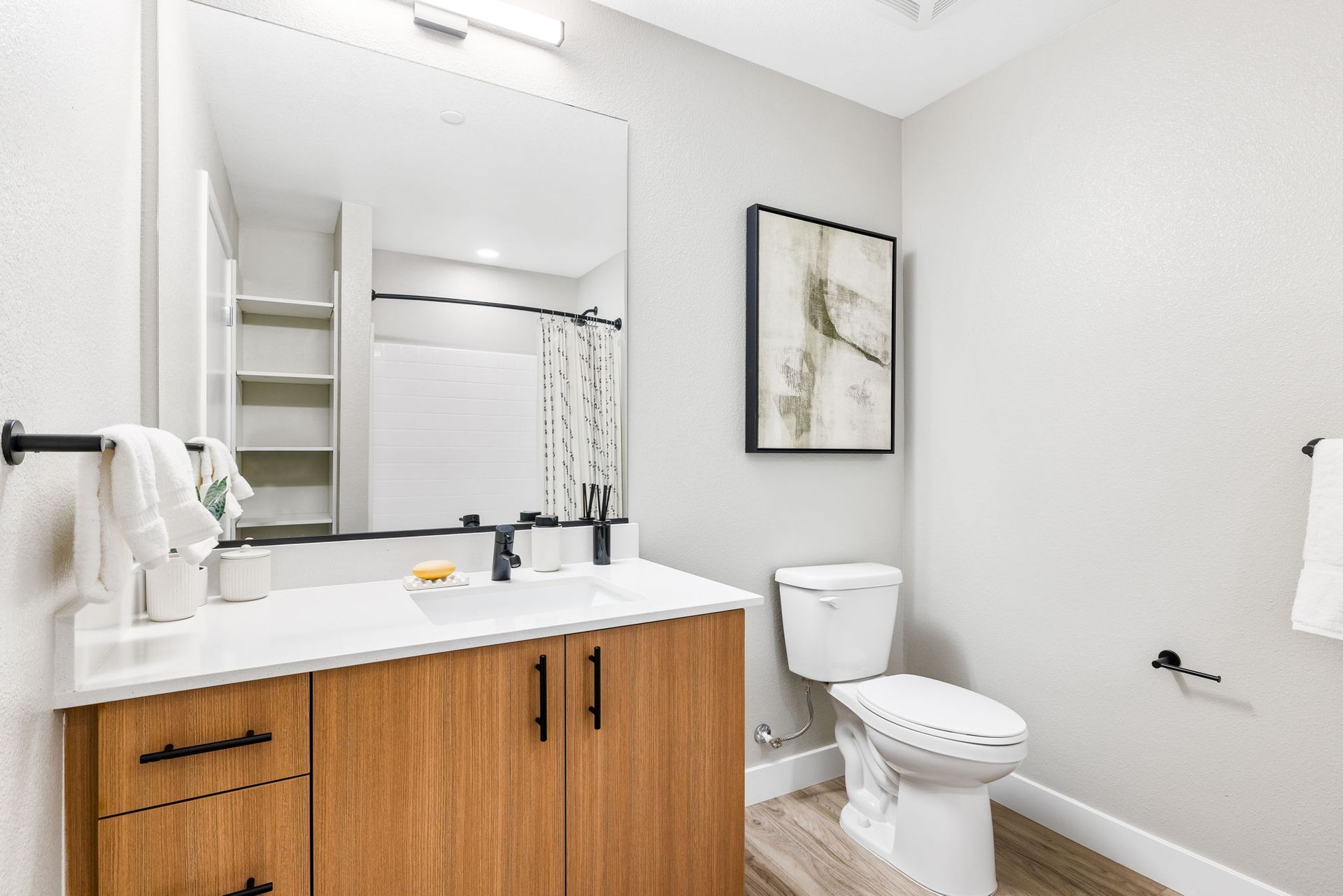A bathroom with a toilet , sink and mirror.