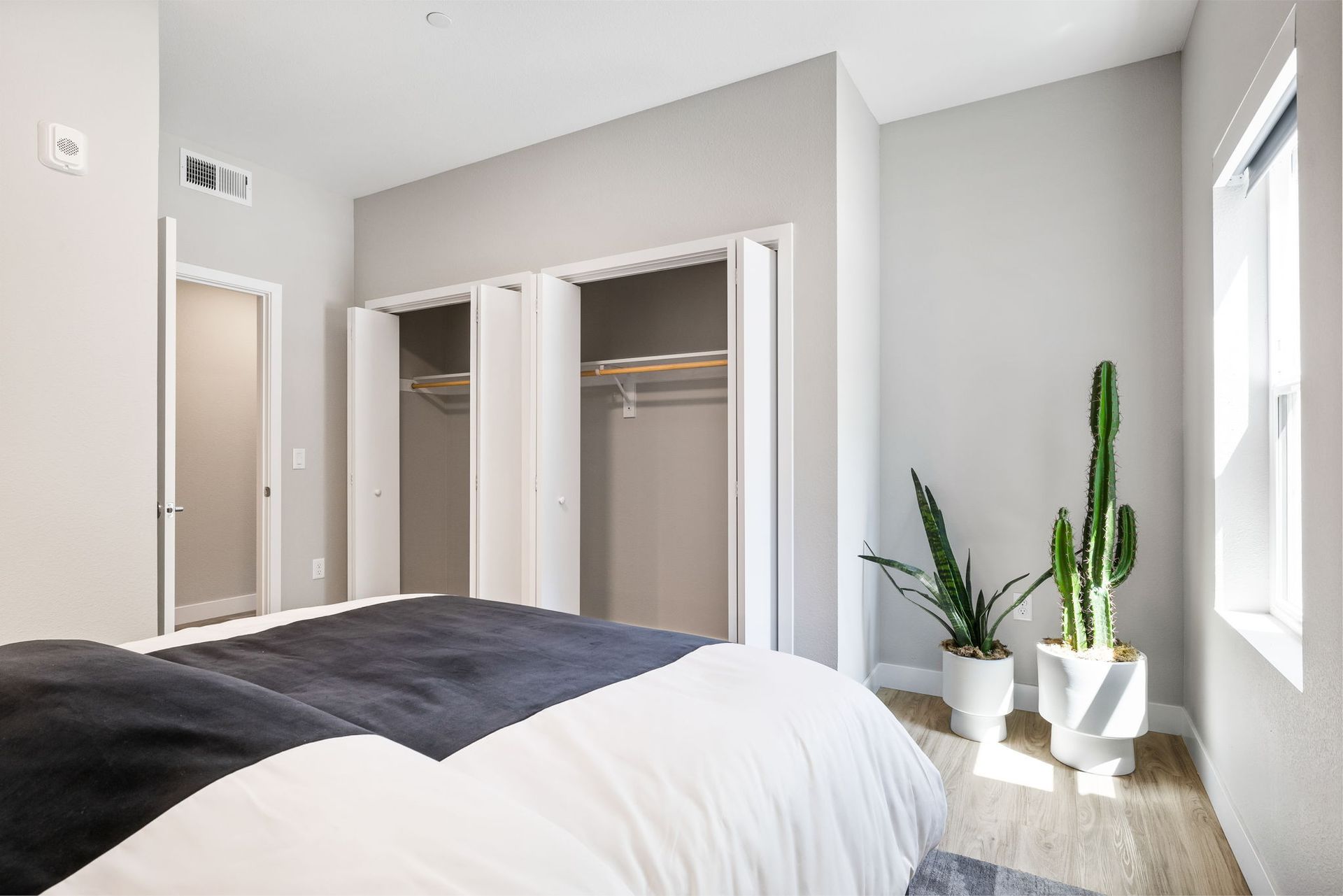 A bedroom with a bed , closets and a window.