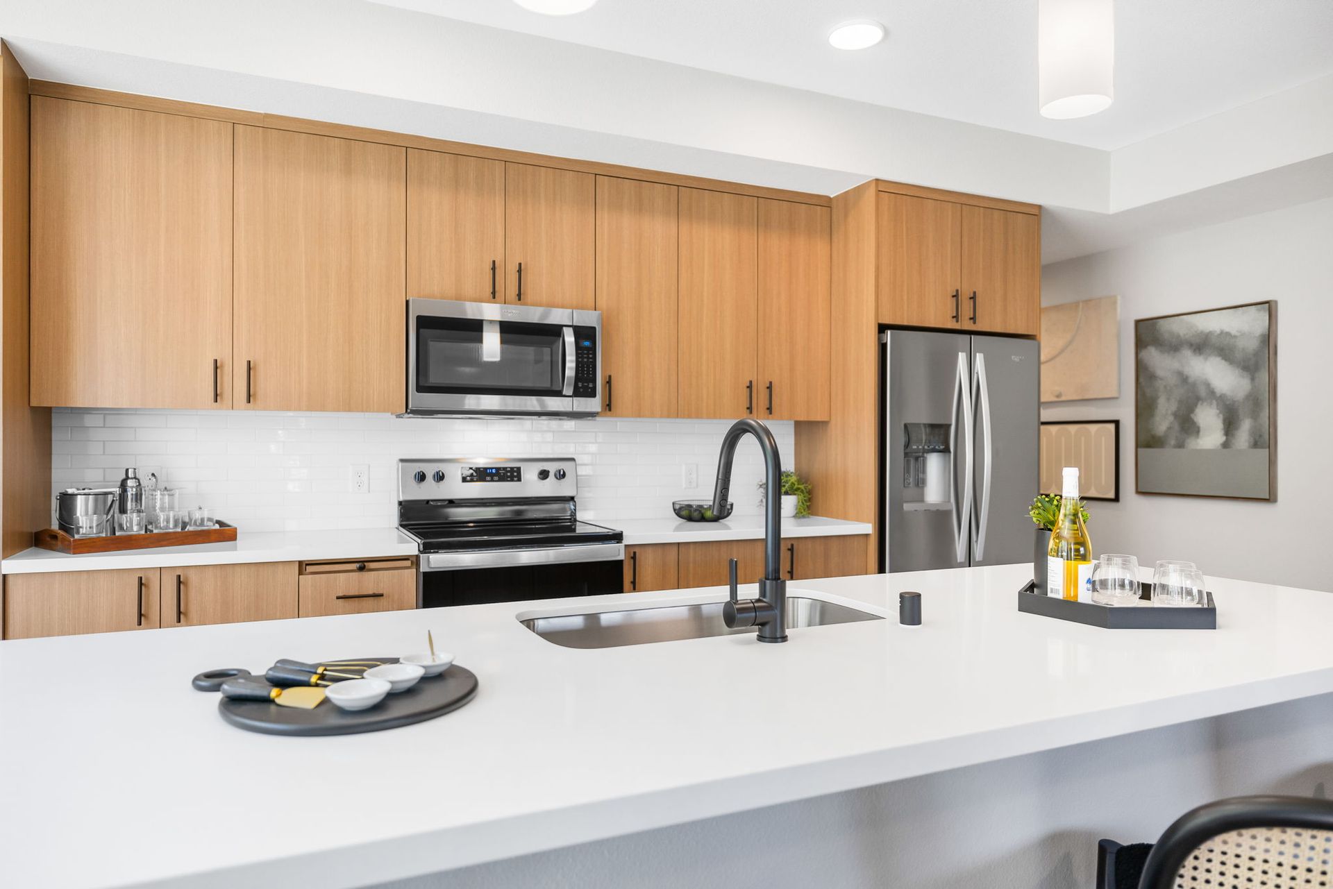 A kitchen with wooden cabinets , stainless steel appliances , a sink , and a refrigerator.