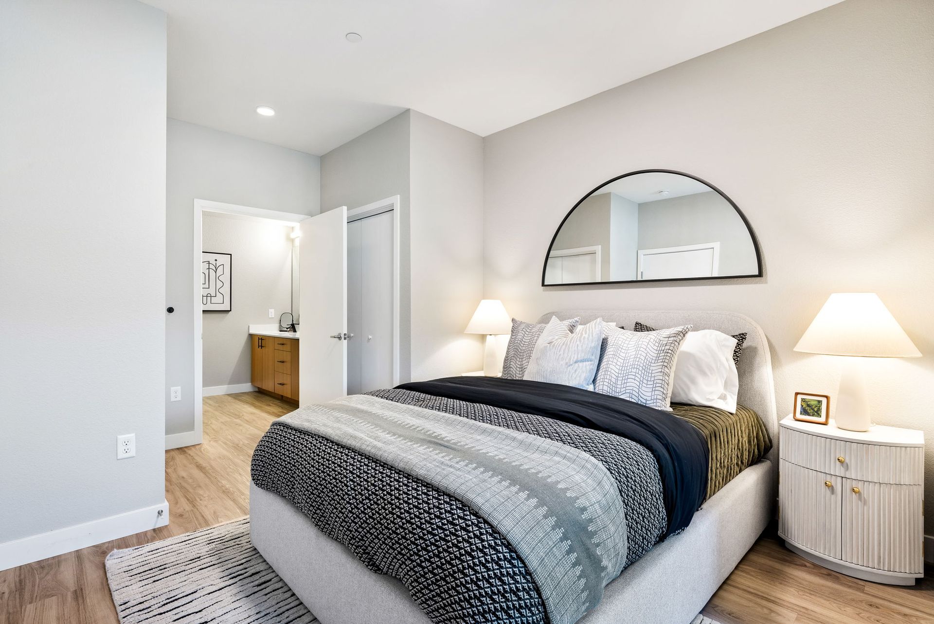 A bedroom with a large bed and a mirror on the wall.