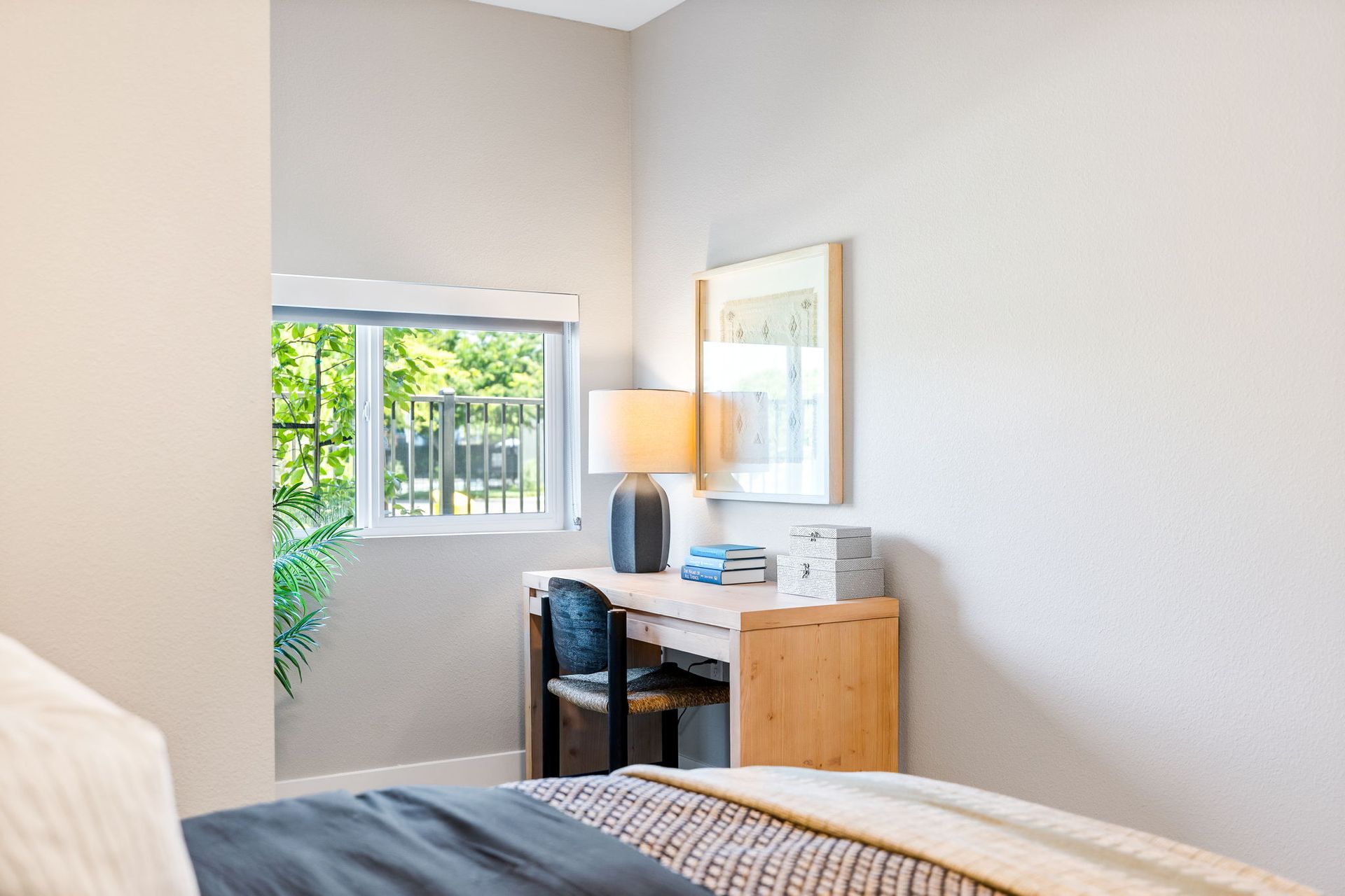 A bedroom with a bed , desk , lamp and window.