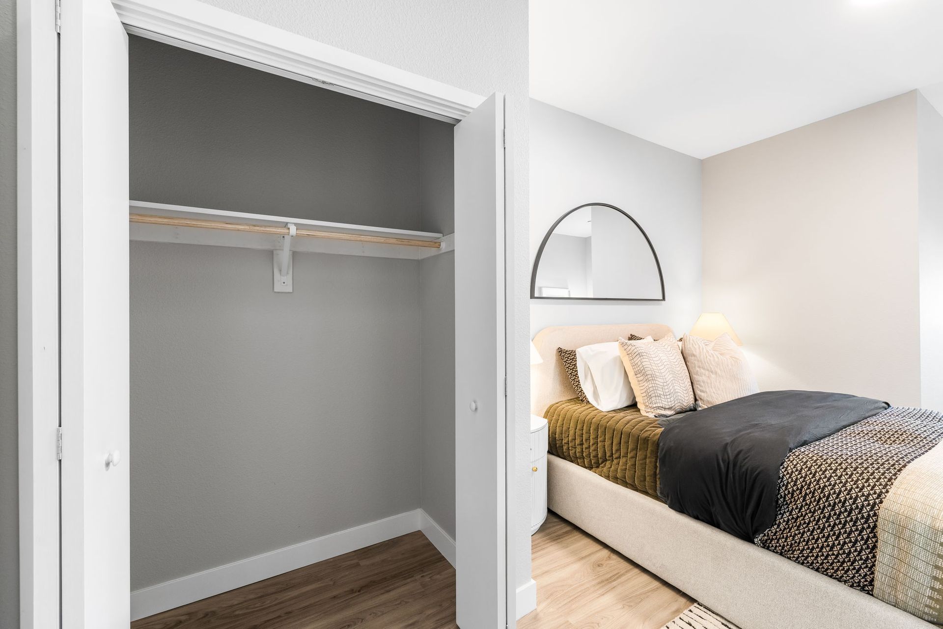 A bedroom with a bed , closet and mirror.