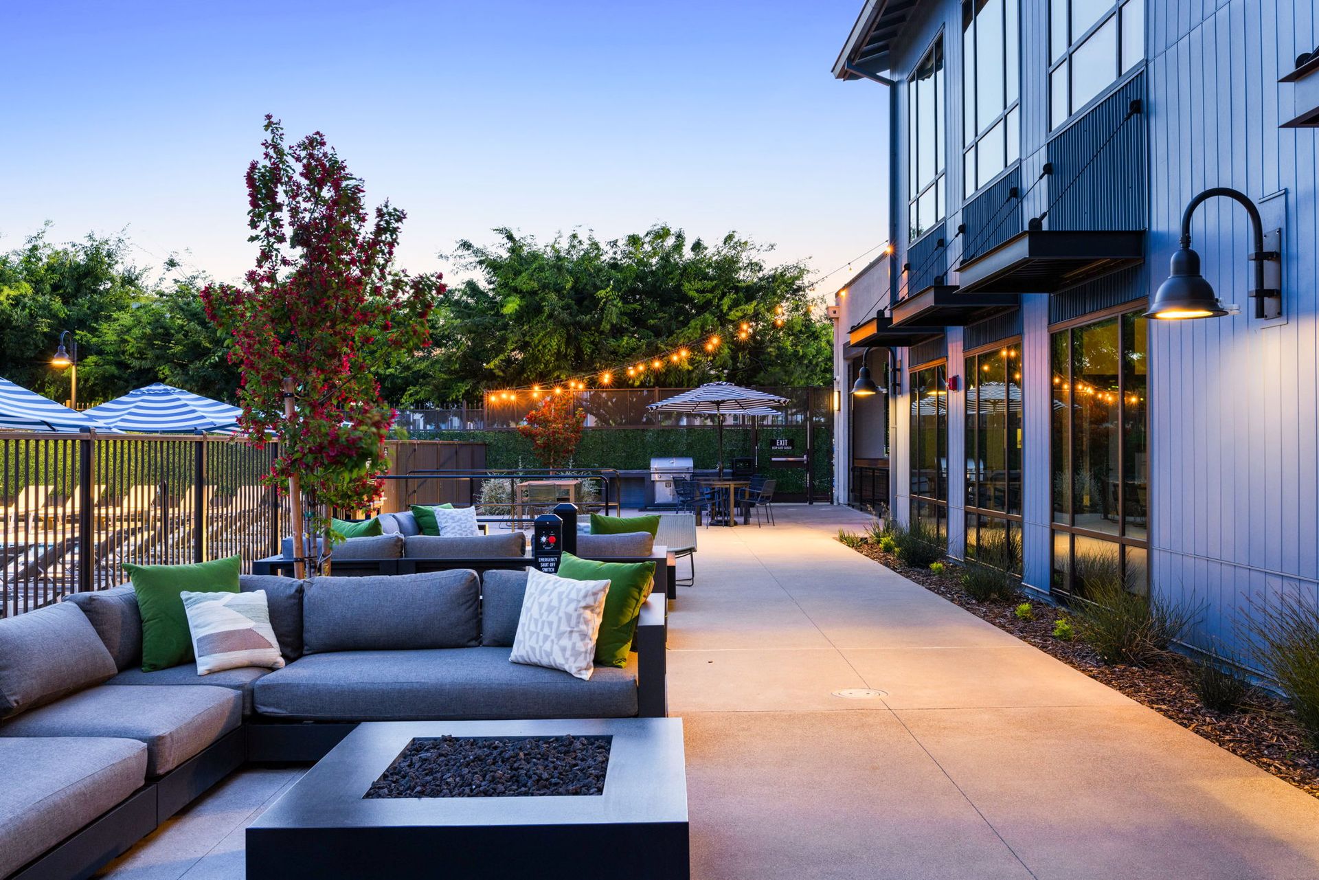 A patio with a couch and a fire pit in front of a building.
