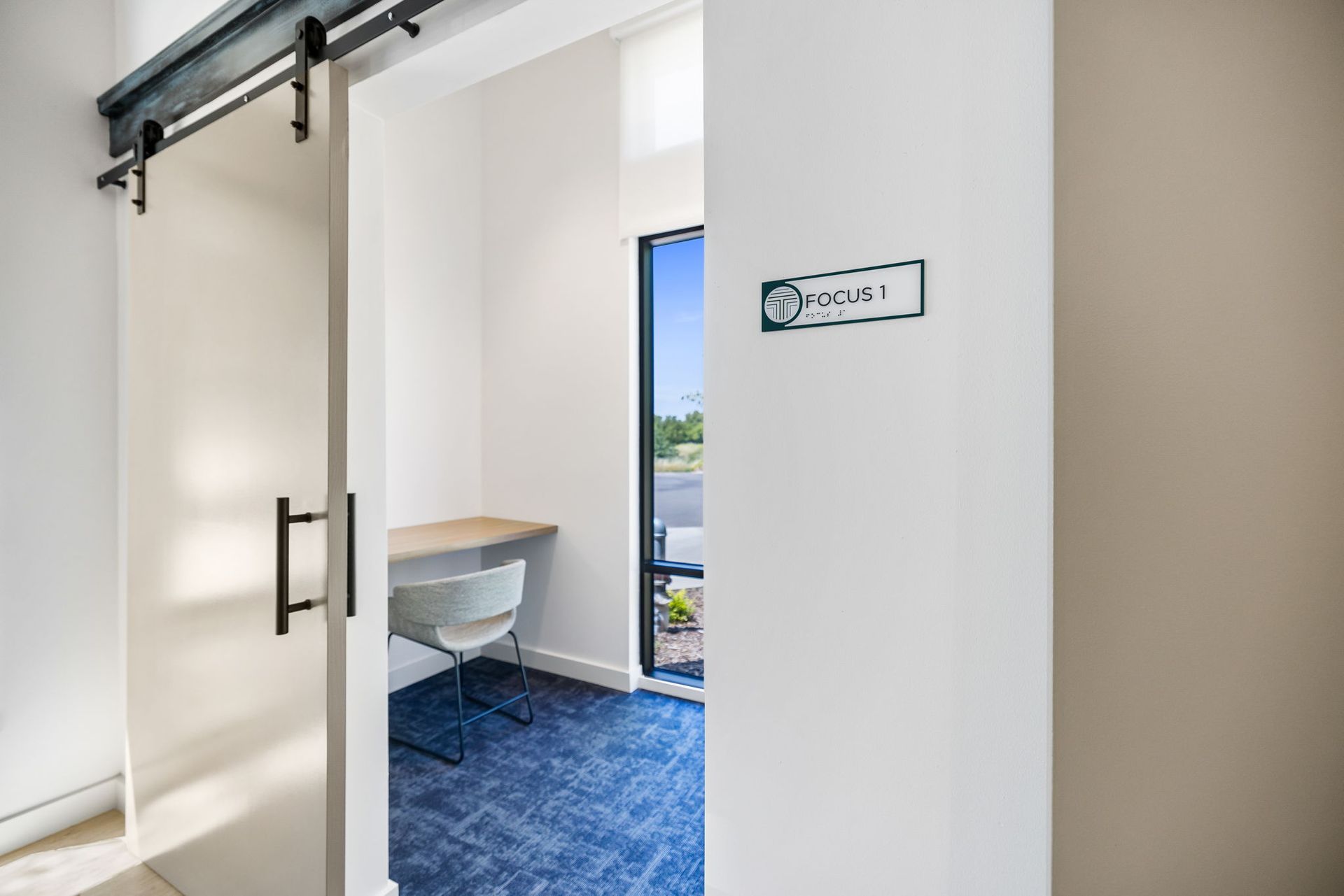 A private work room with a sliding barn door and a desk.