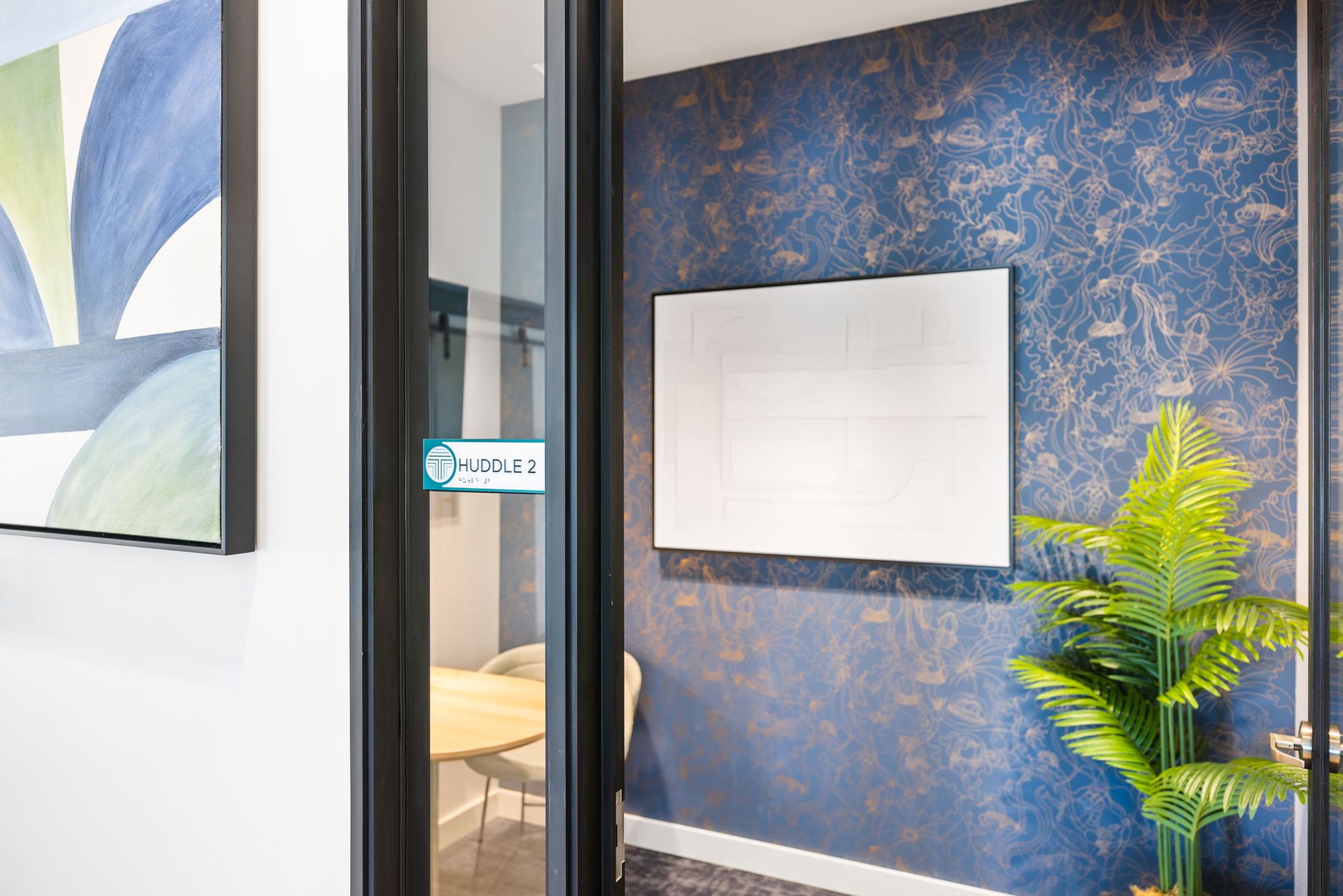 A conference room with a table and chairs and a whiteboard on the wall.