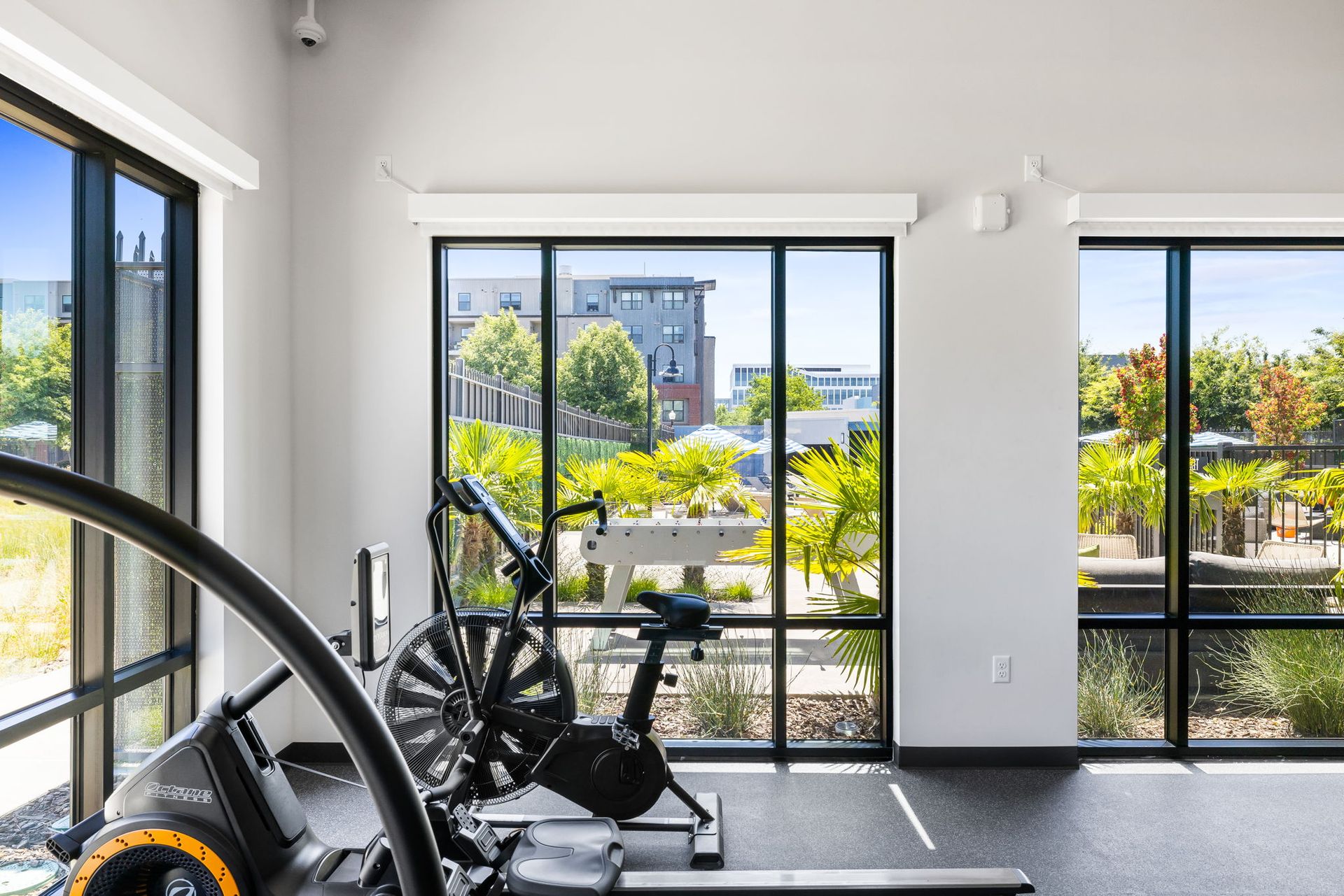 A gym with a bike , treadmill , and large windows.