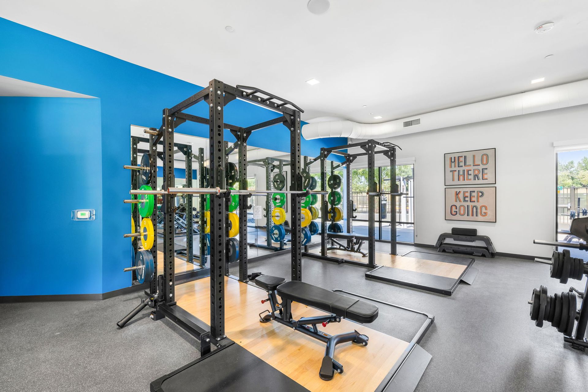 A gym with a lot of equipment and a blue wall.
