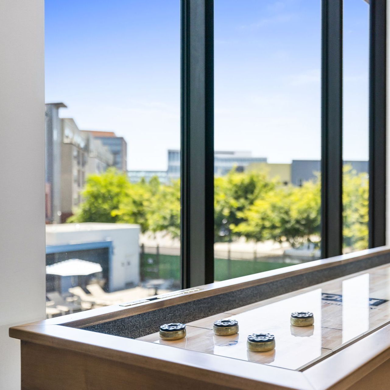 Bright room with large windows, a shallow tray on a table, and trees and buildings outside at The Hayley in Sacramento, CA.