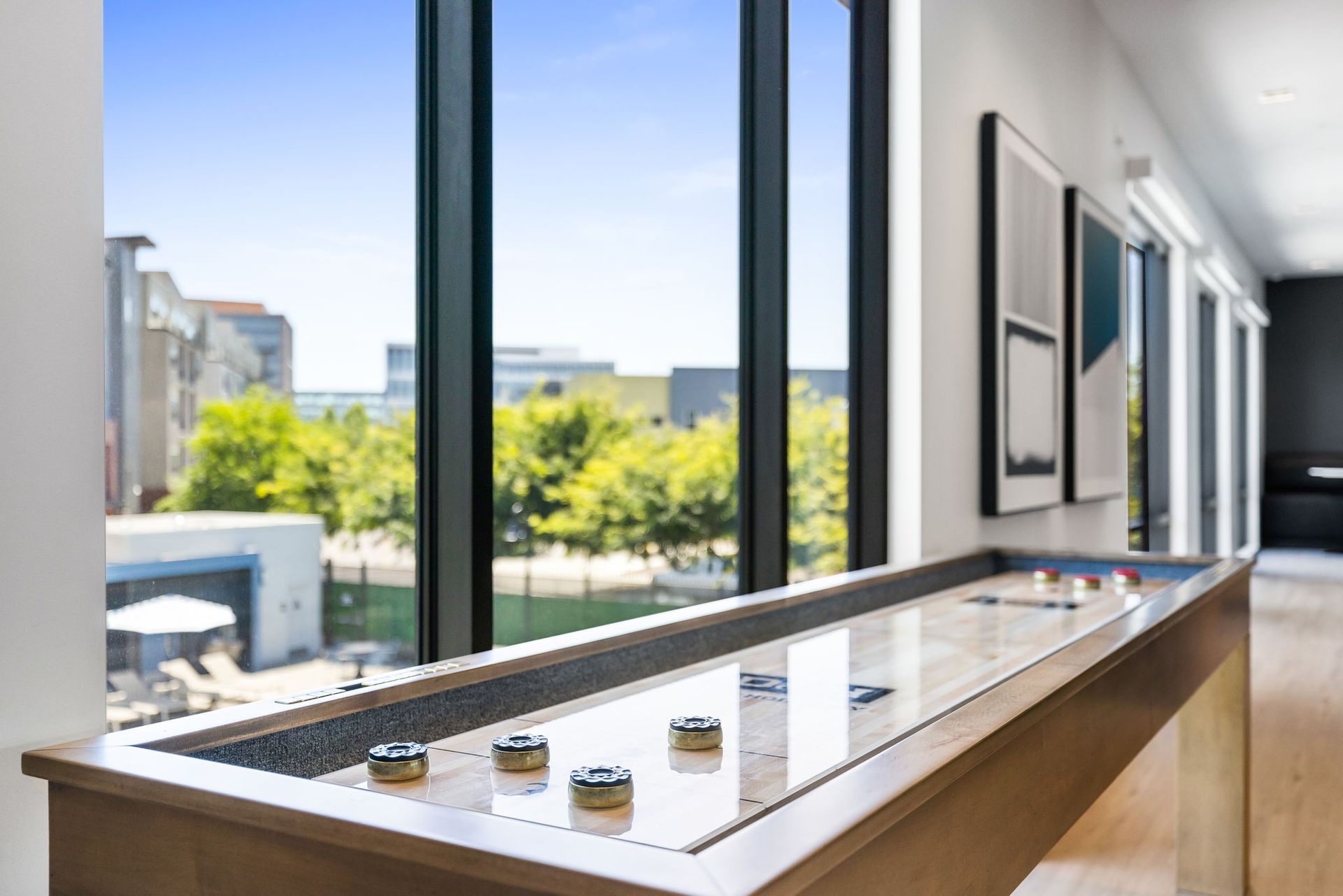 A shuffleboard table in a game room next to a window.