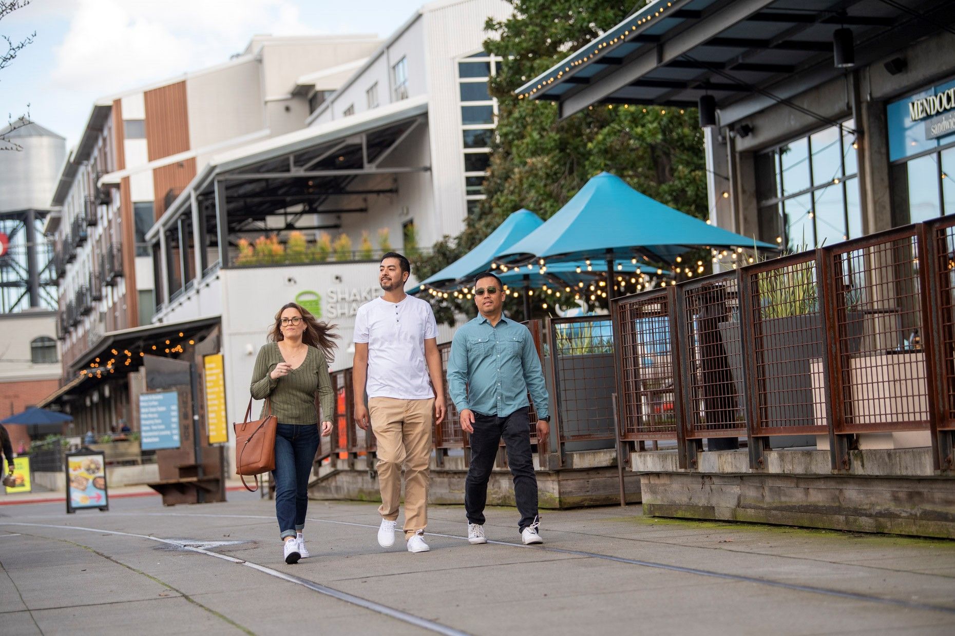 A group of people are walking down a sidewalk in front of a building.