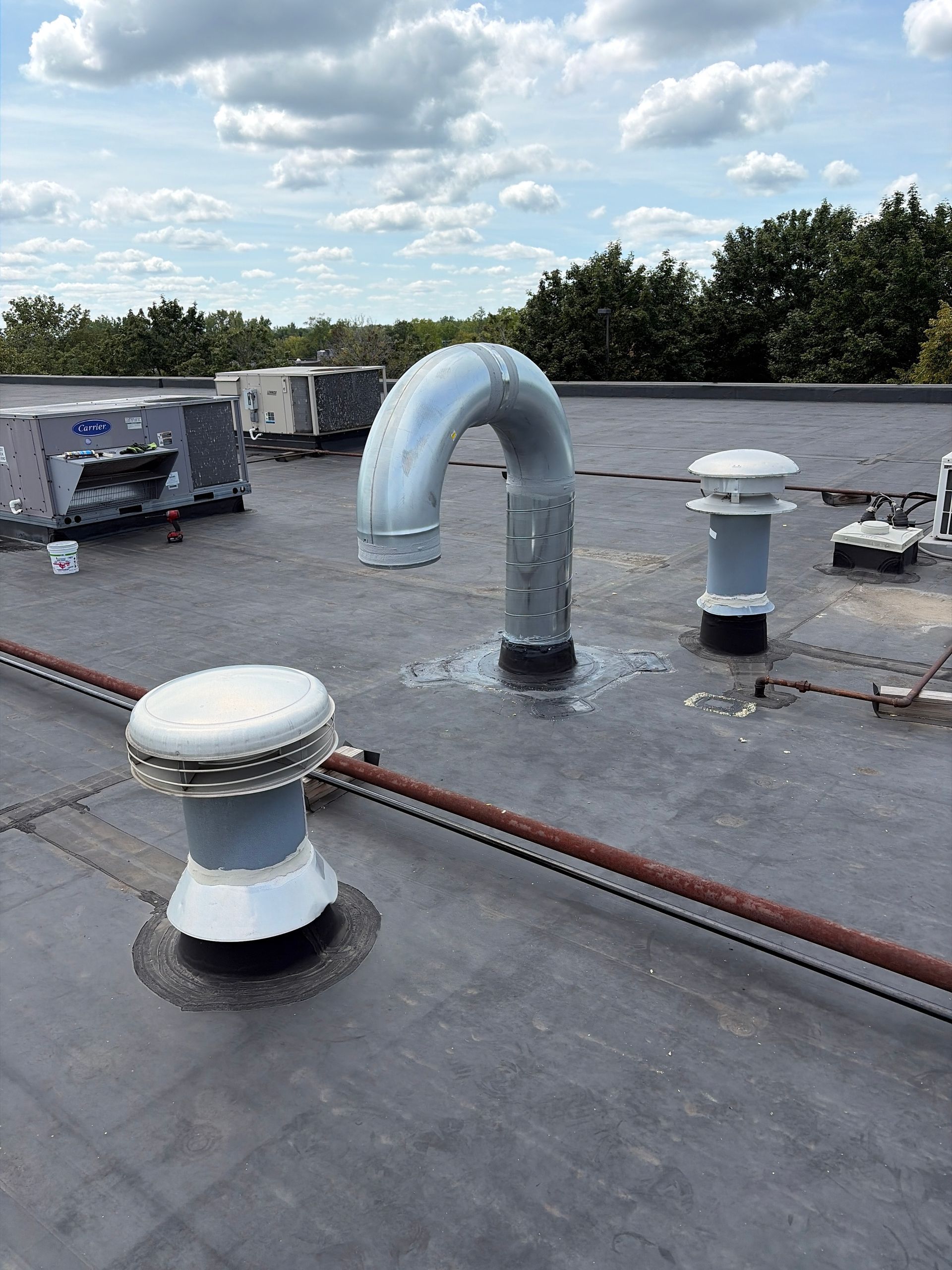 Rooftop with ventilation pipes and vents under a cloudy sky