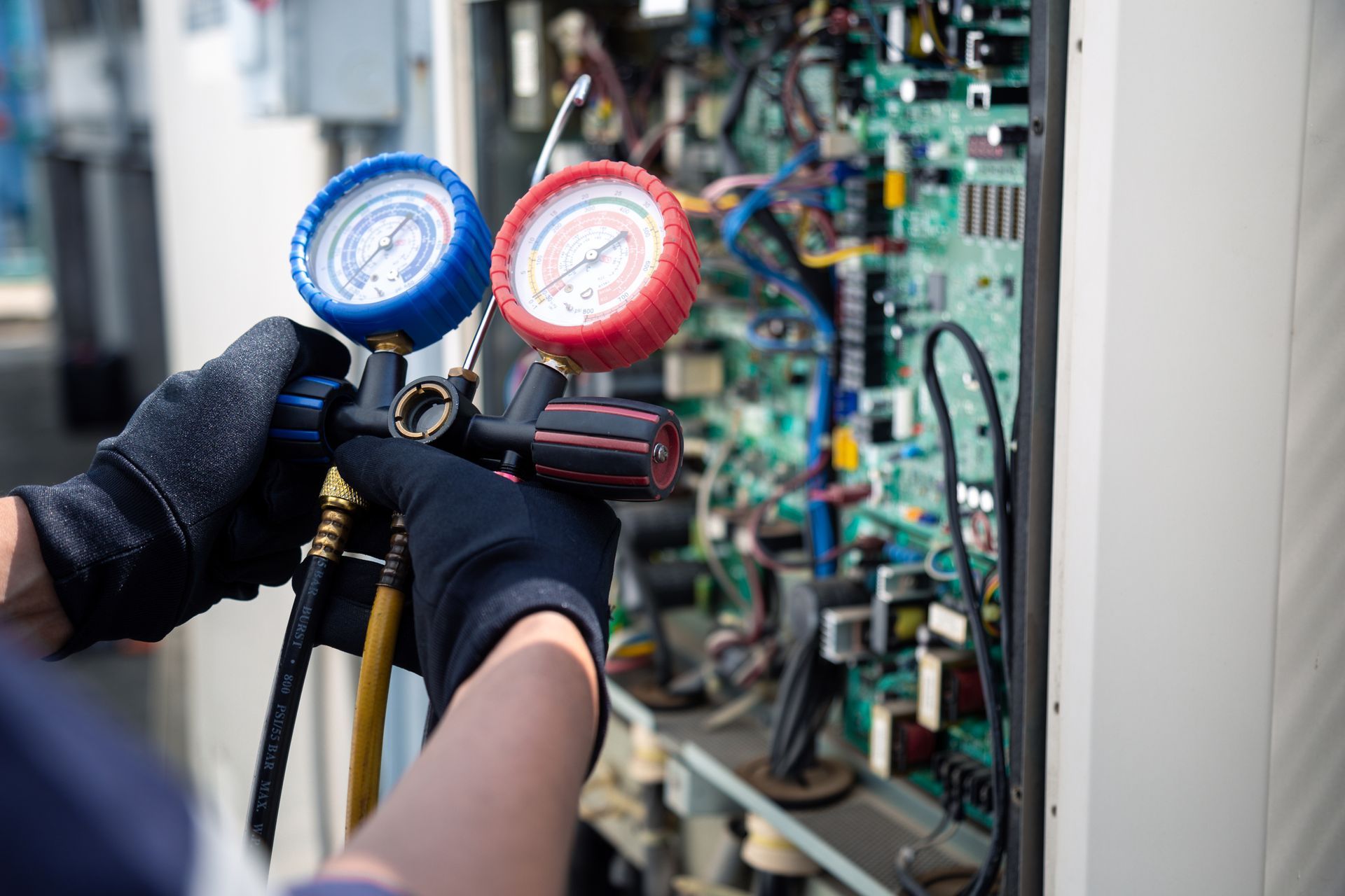 Gloved hands using blue and red gauges to service industrial equipment in a control panel cabinet Gloved hands using blue and red gauges to service industrial equipment in a control panel cabinet