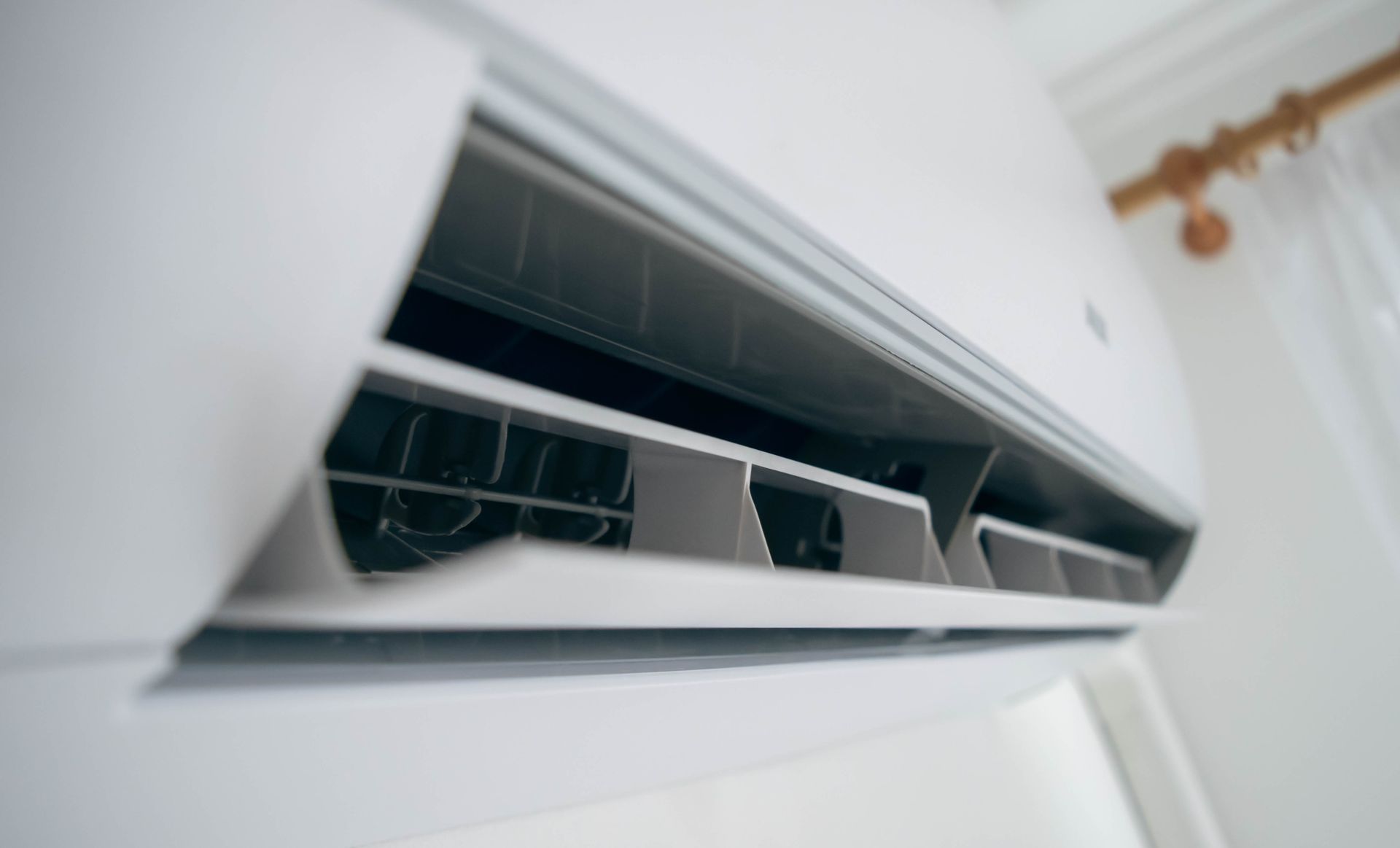 White wall-mounted air conditioner with open vents in a bright room White wall-mounted air conditioner with open vents in a bright room