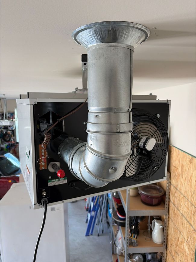 Metal duct and vent fan mounted inside a wall opening, with exposed pipes and wiring. Metal duct and vent fan mounted inside a wall opening, with exposed pipes and wiring.