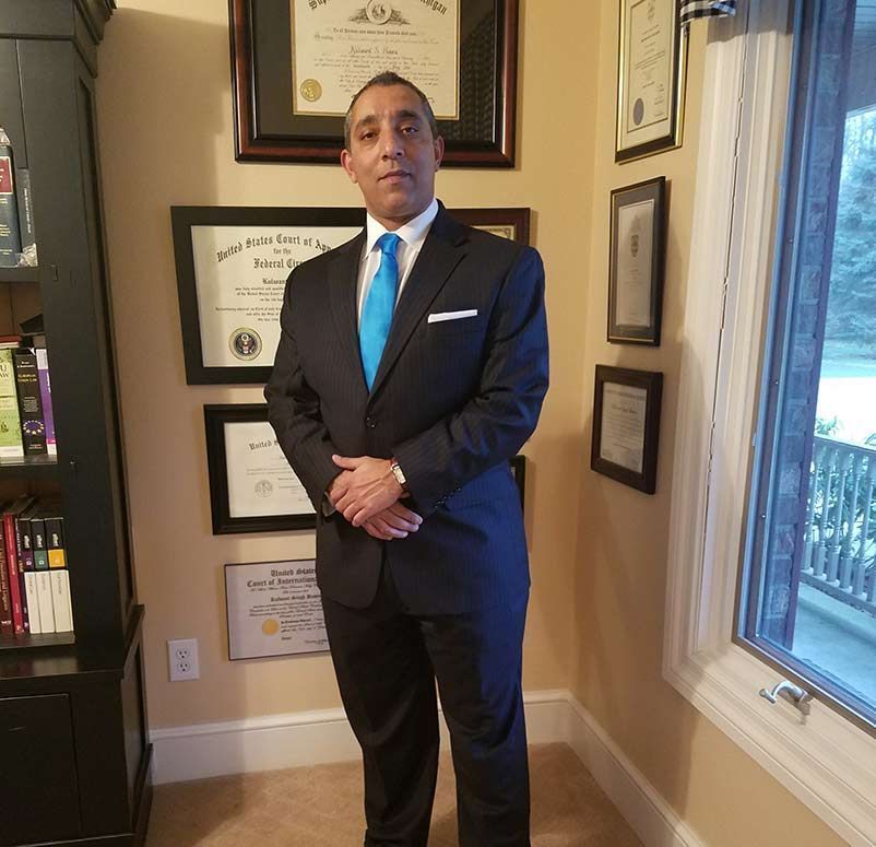 A man in a suit and tie is standing in front of a window