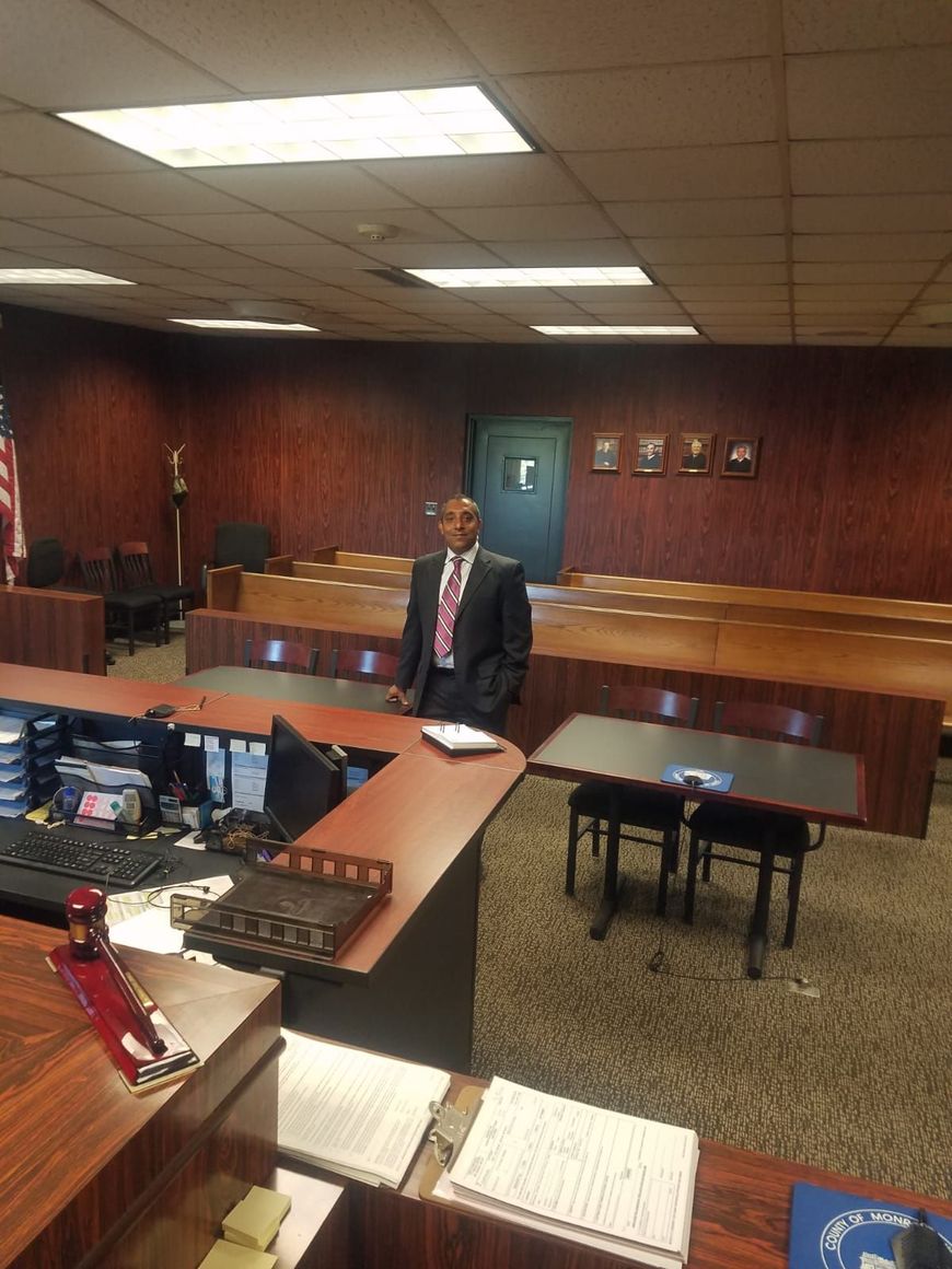 A man in a suit and tie is sitting at a desk in a courtroom