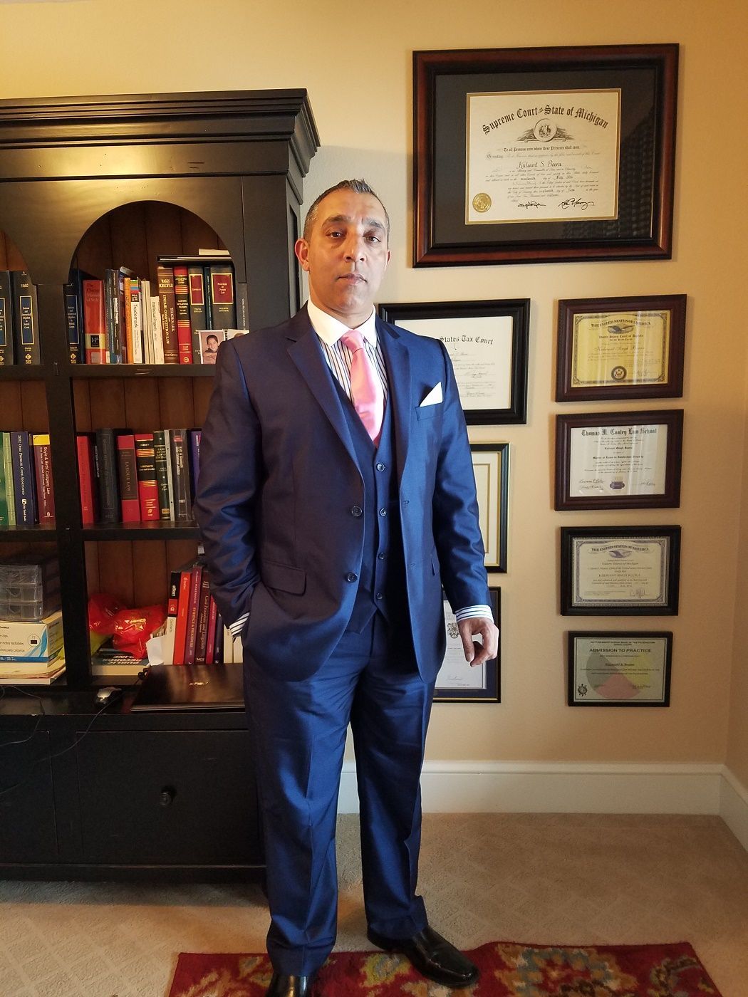 A man in a suit and tie is standing in front of a bookshelf