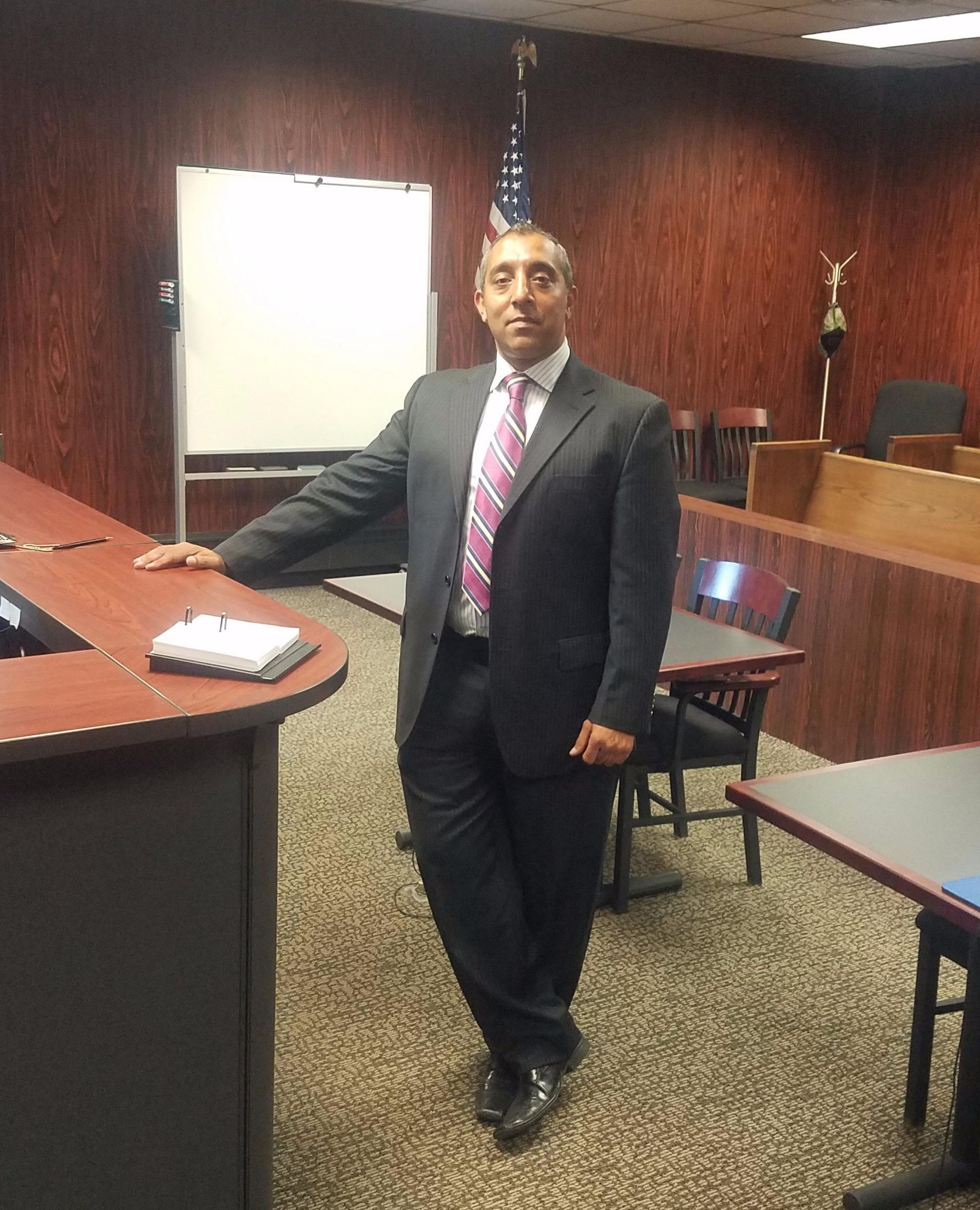 A man in a suit and tie is standing in a courtroom