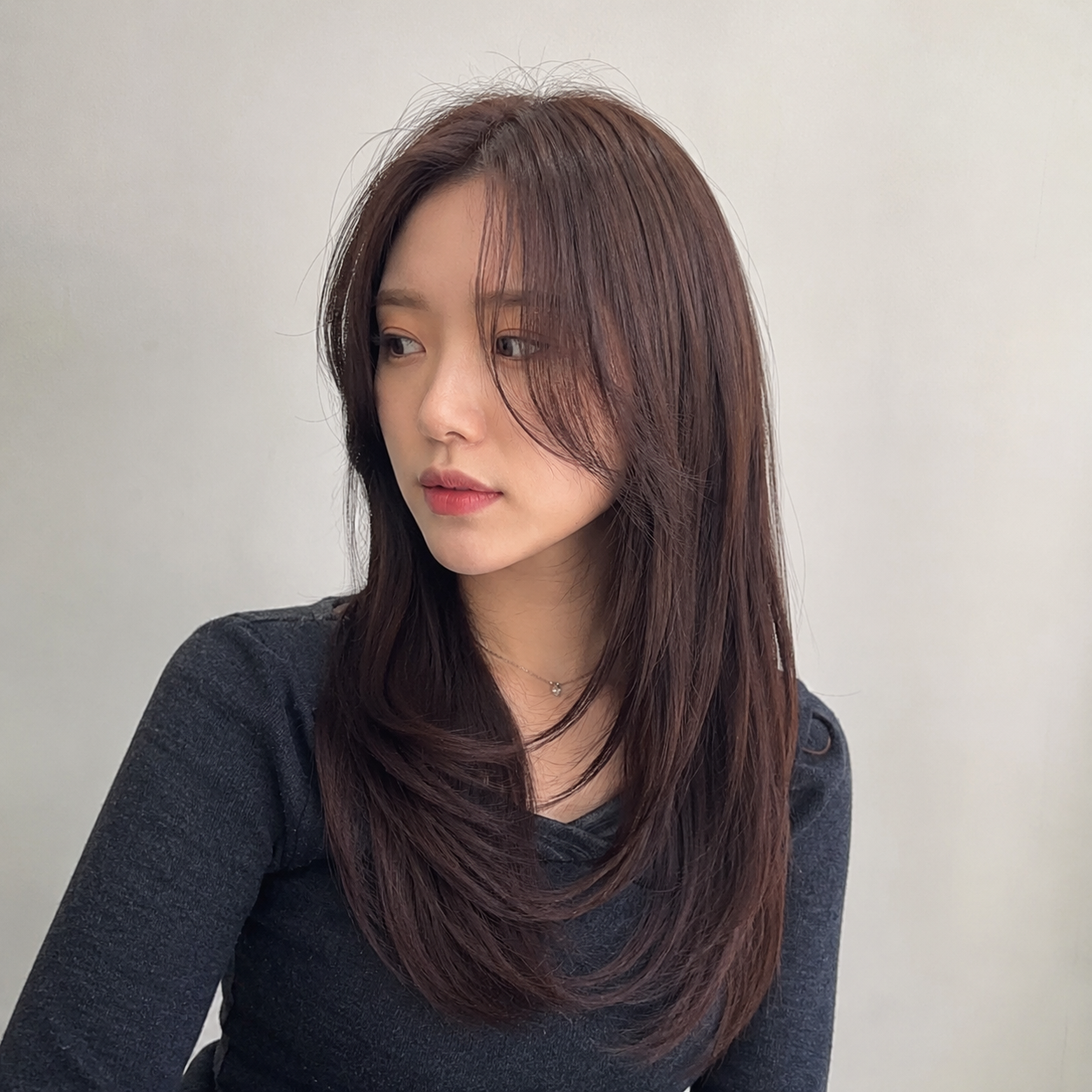 Portrait of a woman with long dark hair in a black top against a plain light background at busan gwangalli haeundae