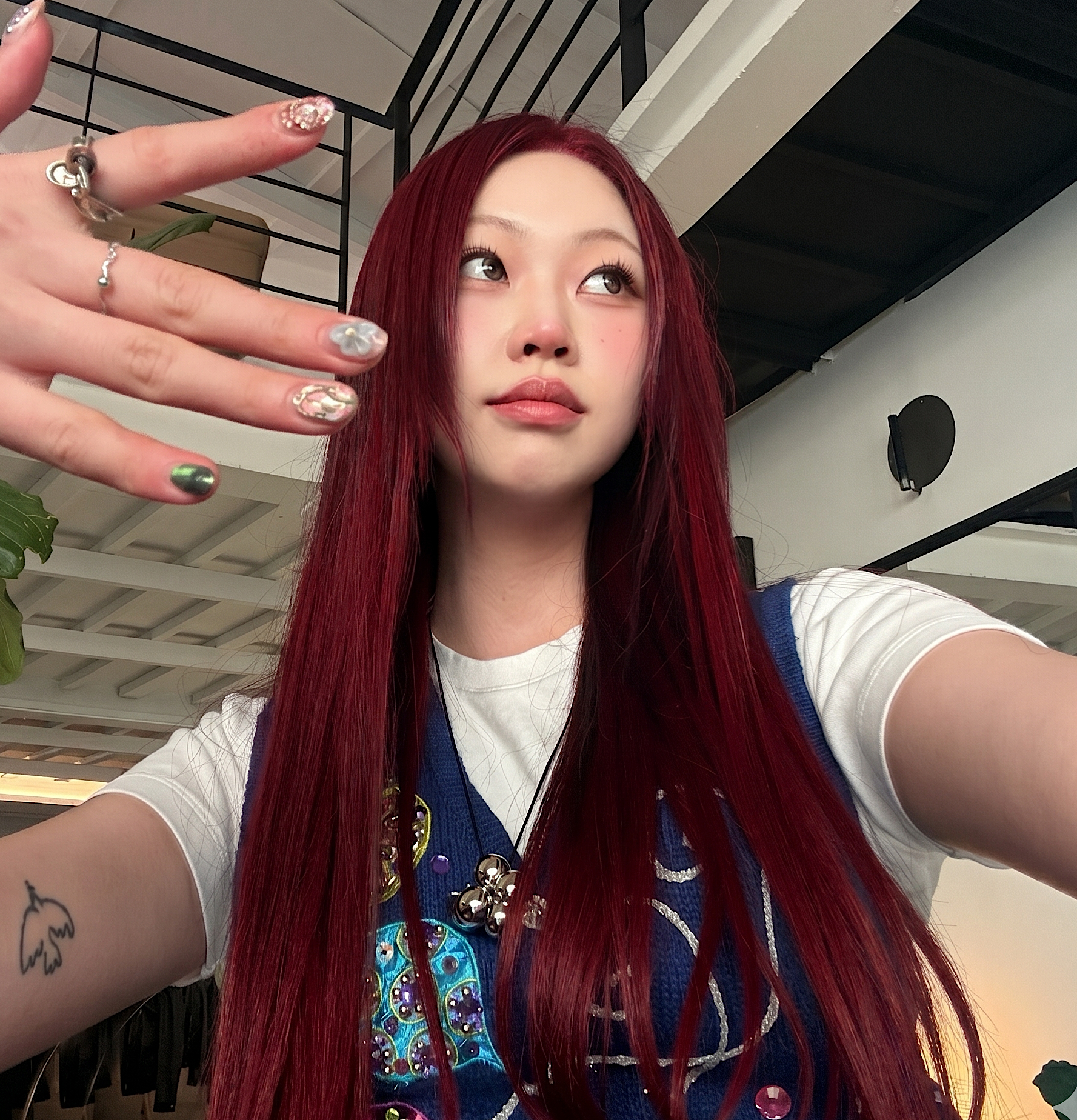 Woman with long red hair holding up a hand, wearing a blue top indoors on a stairway at busan gwangalli haeundae