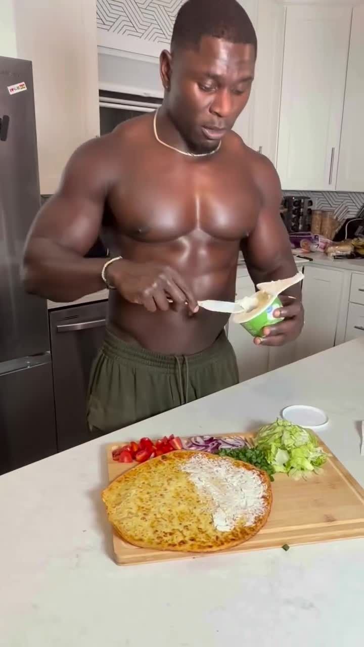 Person in a kitchen scooping food from a cup onto a plate of noodles, rice, and vegetables.