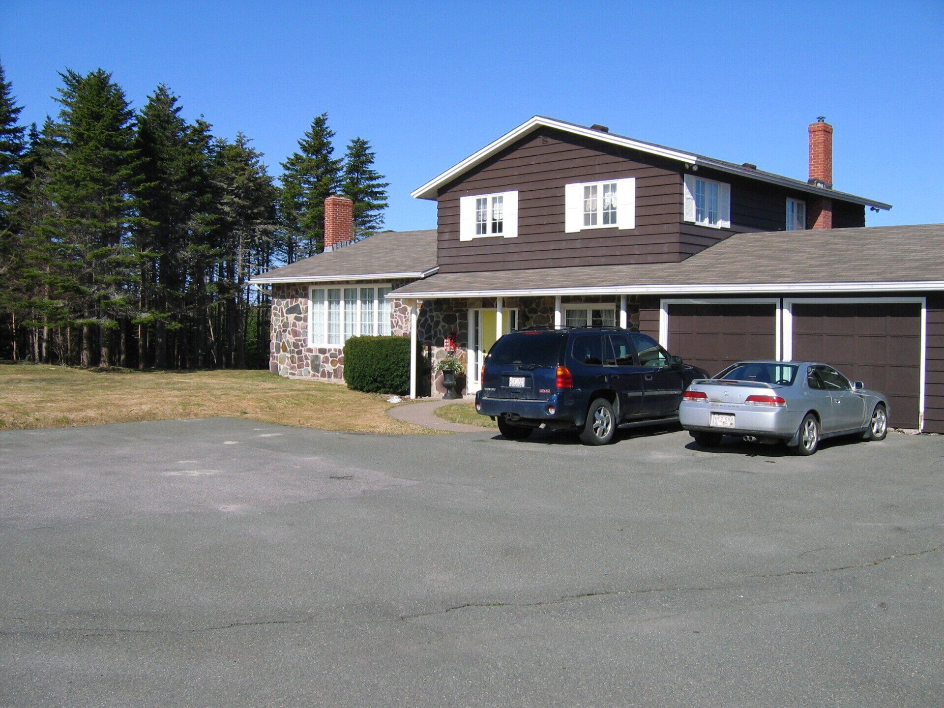 Two cars are parked in front of a large house