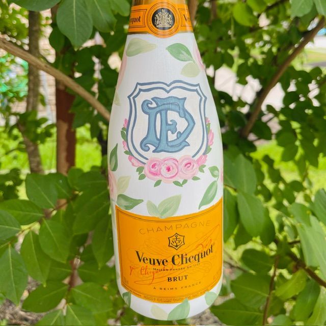Veuve Clicquot Brut champagne bottle with pastel floral design against green leaves