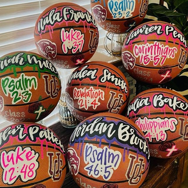 Basketballs decorated with colorful Bible verse names and references, stacked closely together