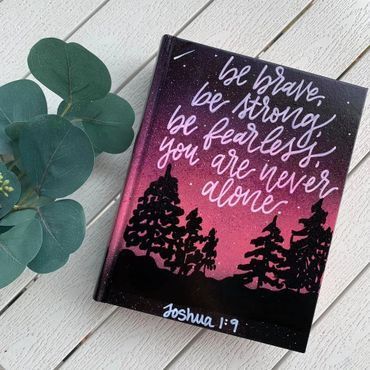 Decorative canvas with sunset sky, silhouetted trees, and the quote “be brave, be strong, be fearless, you are never alone.”