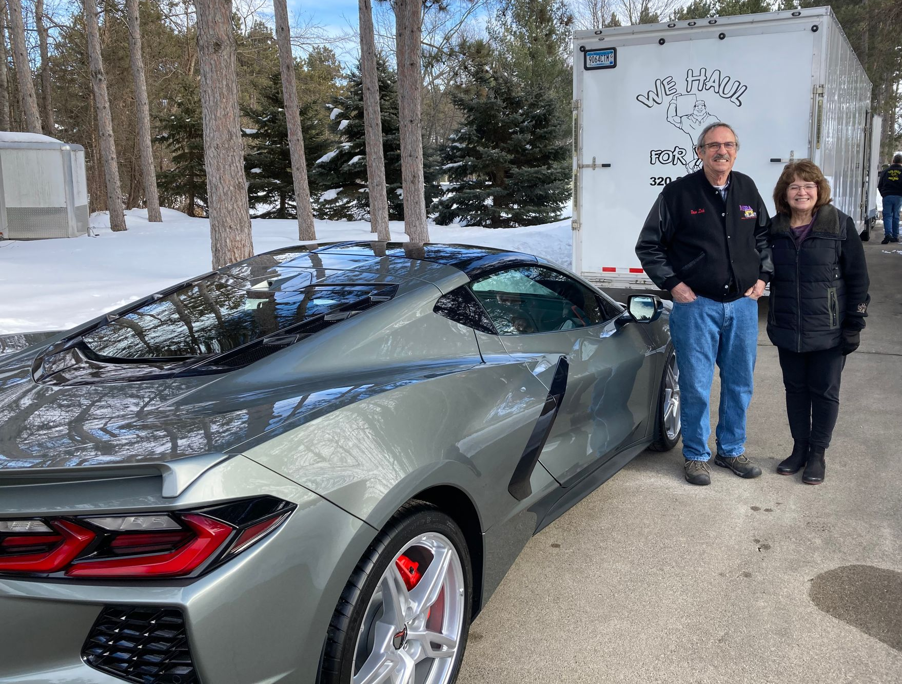 smiling couple with a car in front of company truck