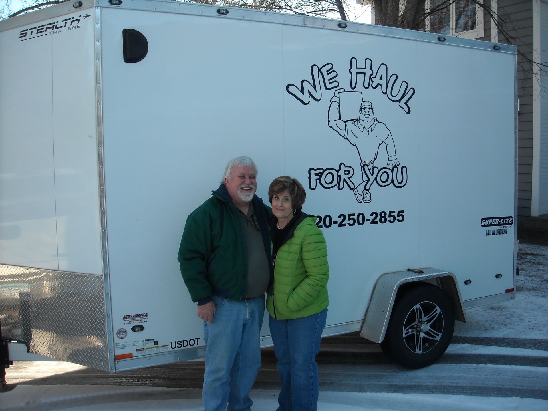 A couple poses in front of a white trailer with 