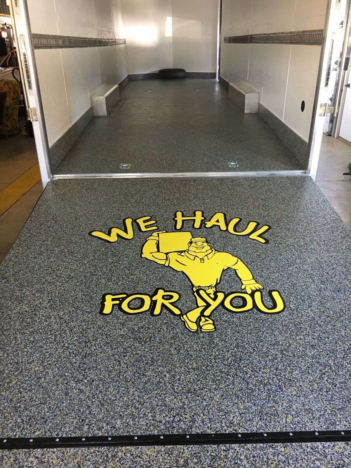Interior of a trailer with a speckled floor, a logo that says 