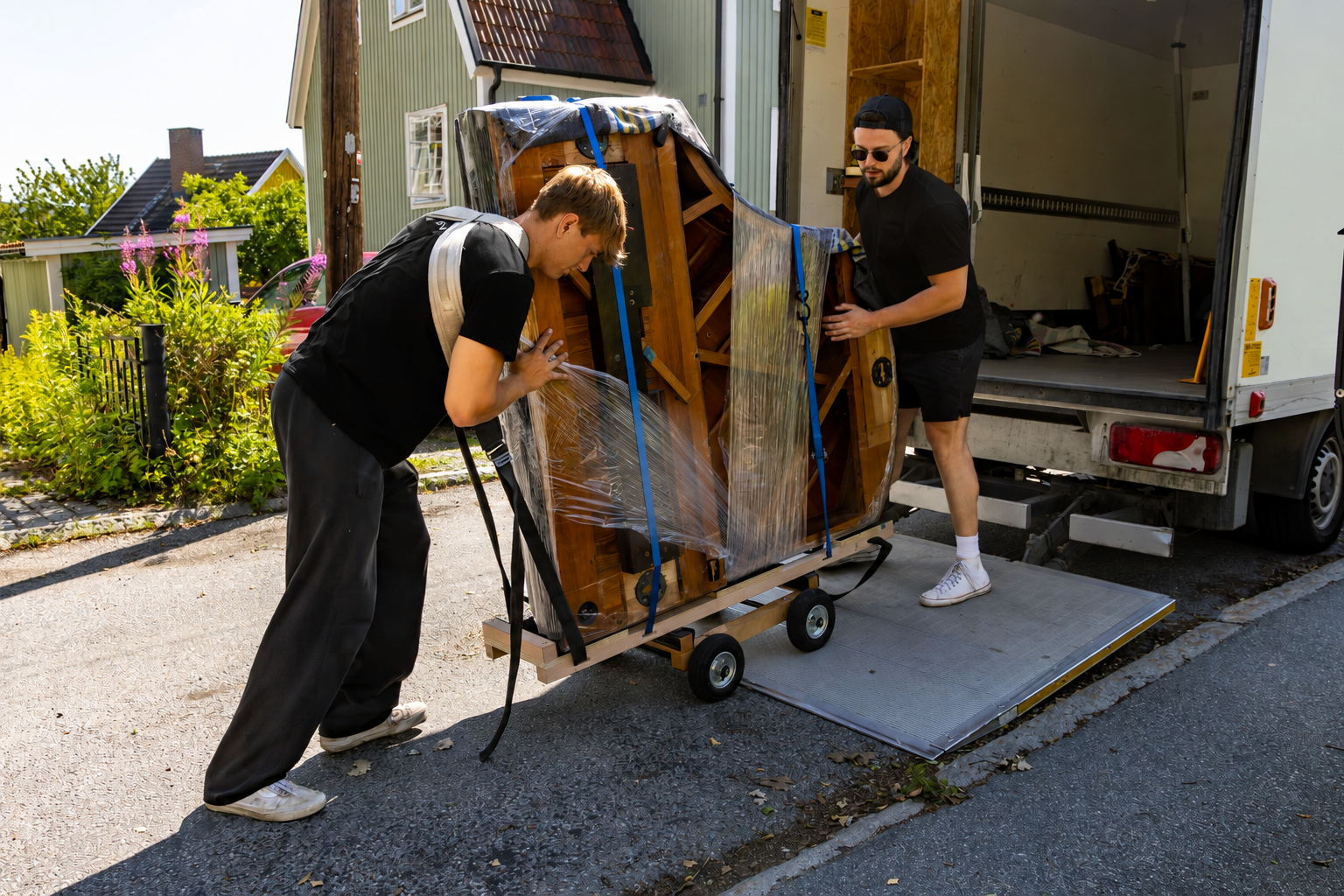 Two employees loading a carefully packed piano into a moving truck