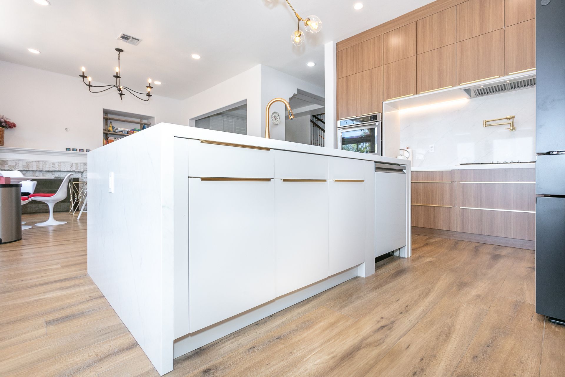 Modern white kitchen with large island, wood floors, and cabinetry.