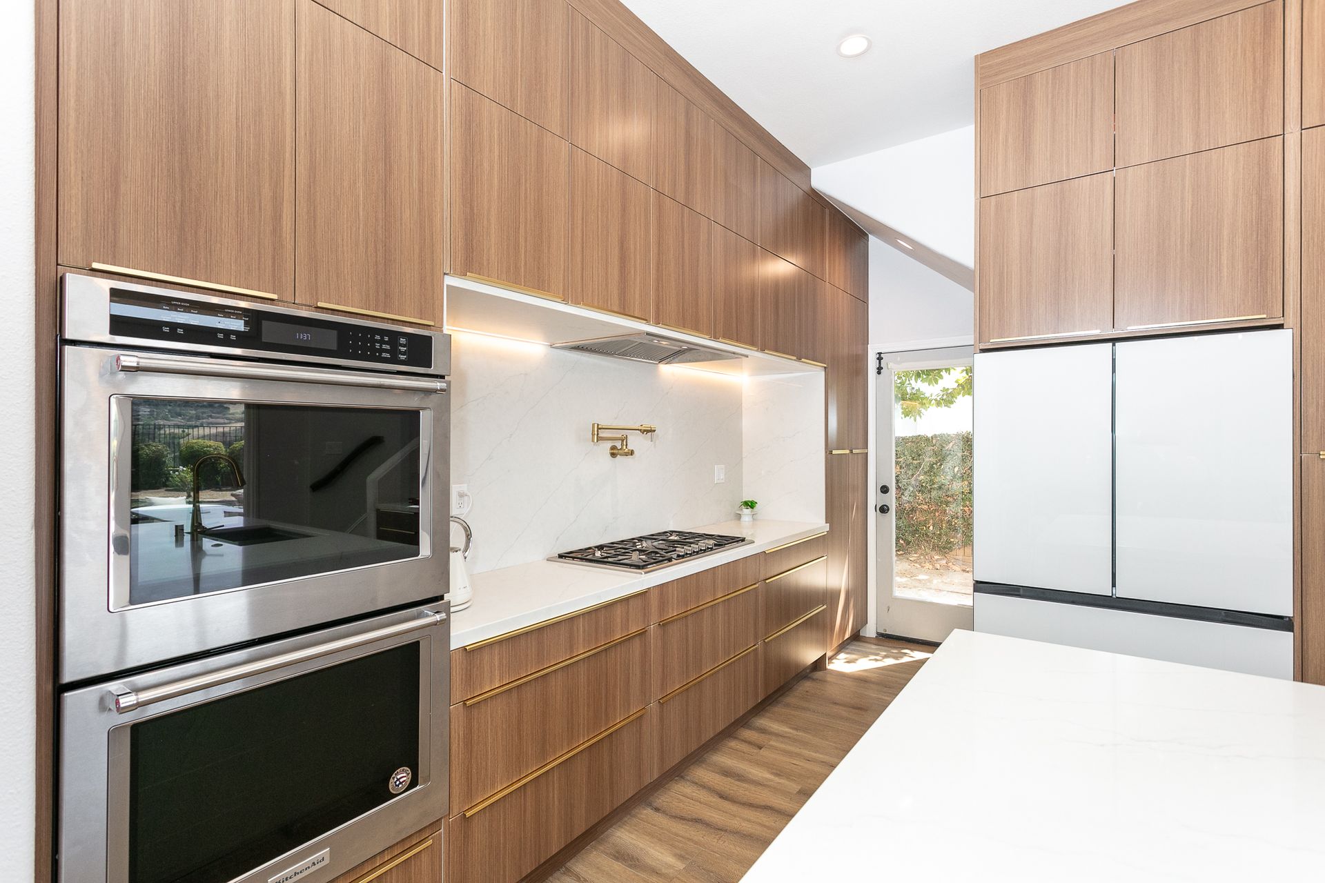 Modern kitchen with wood cabinets, stainless steel appliances, and white countertops.